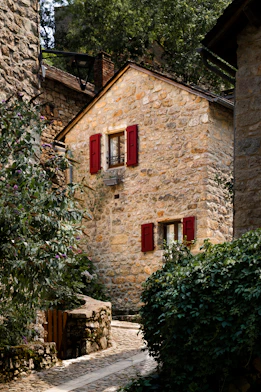 A stone house with red shutters and red shutters