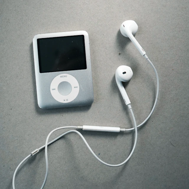 A pair of headphones lying next to an iPod on a table