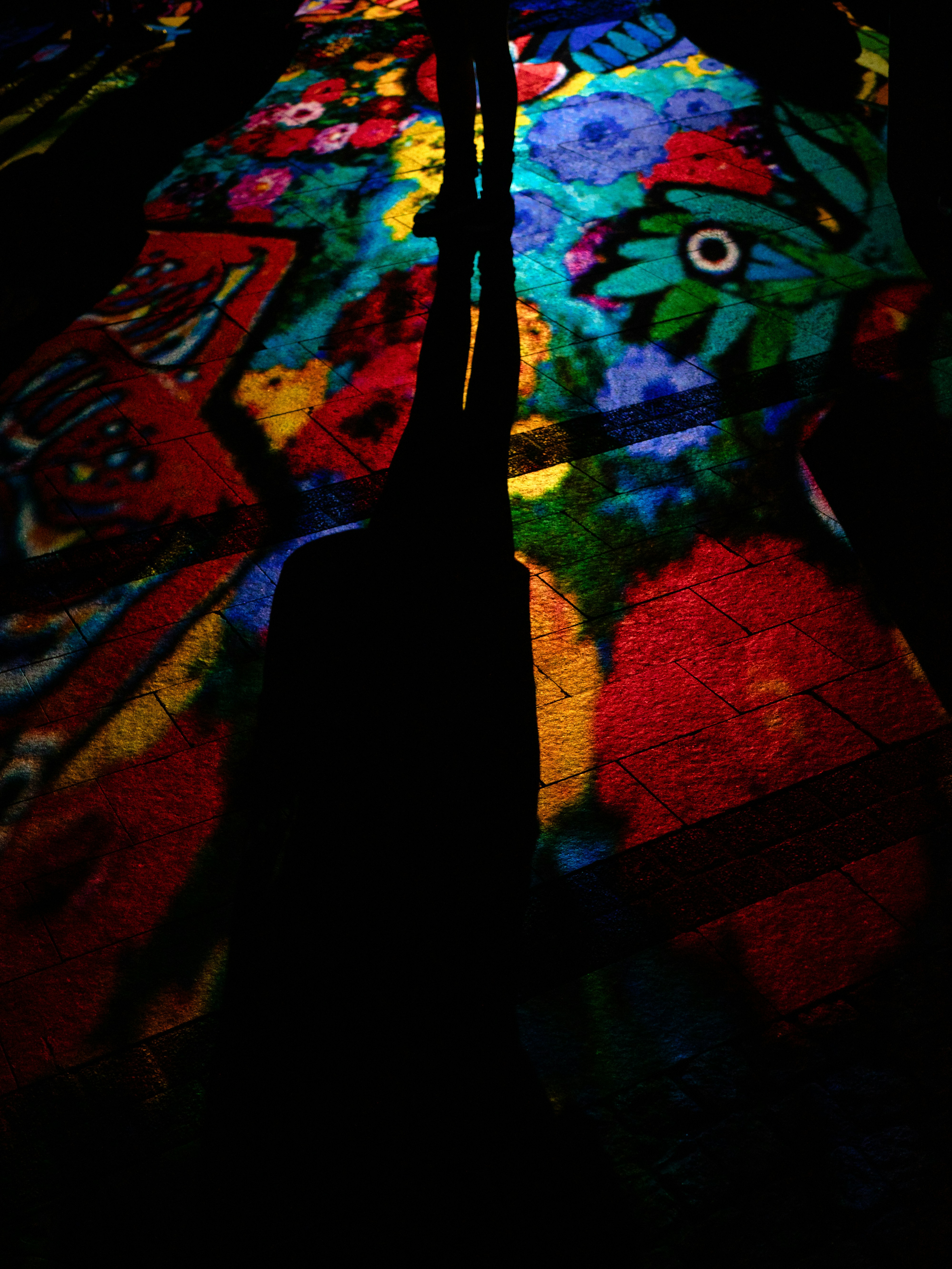 A person standing on a colorful rug in the dark
