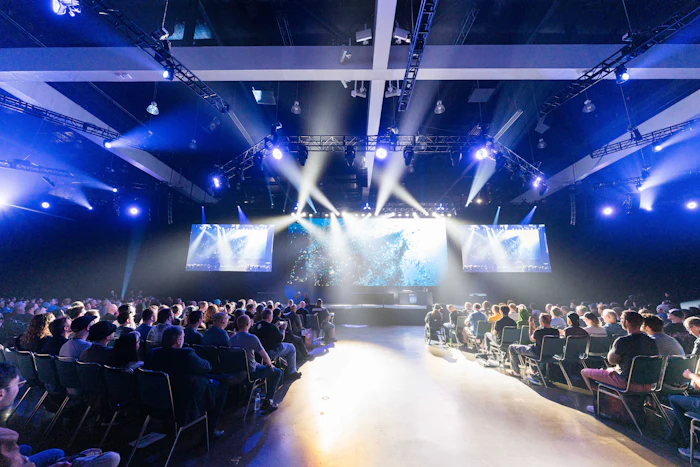 An audience facing a brightly lit stage at a product launch