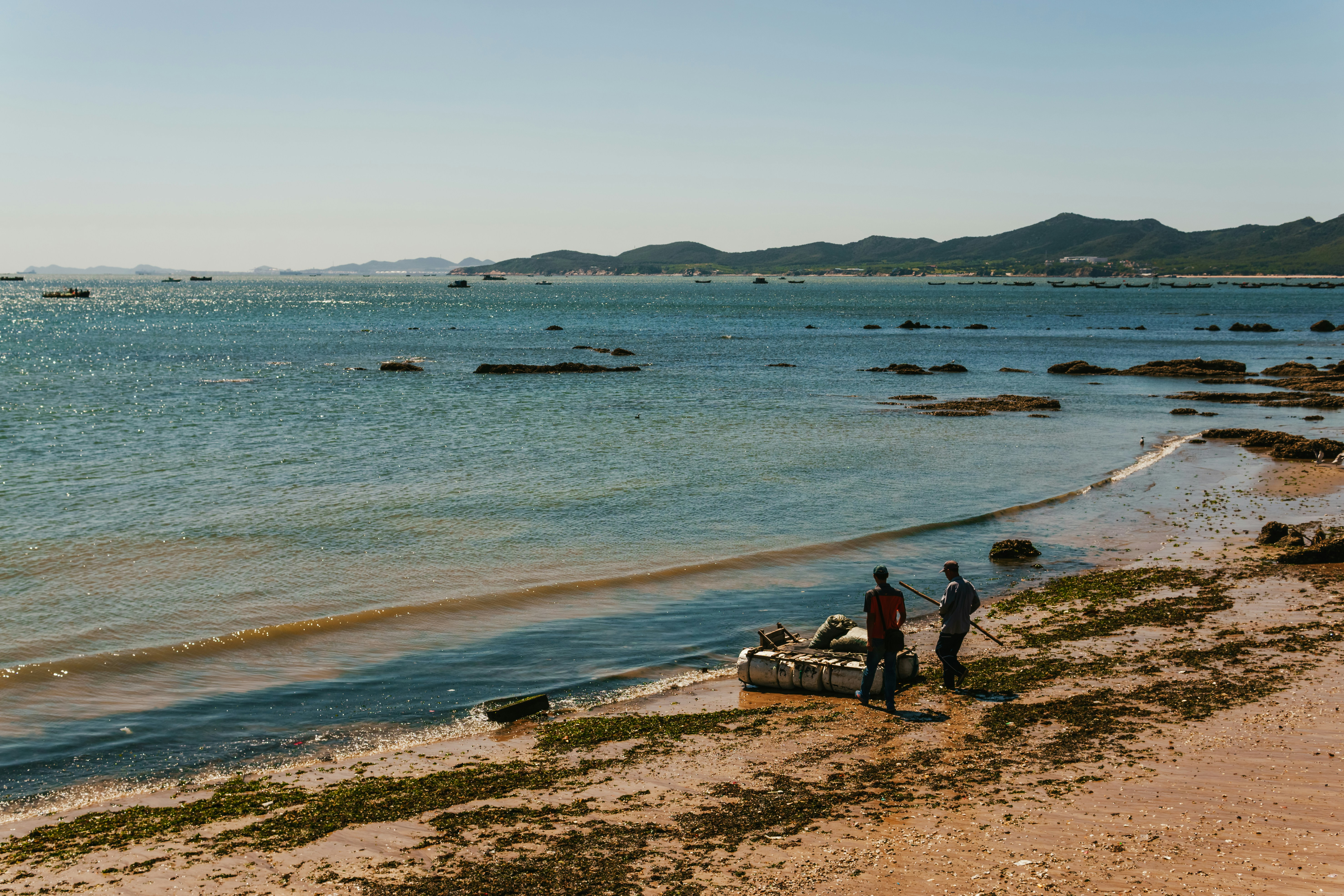 Un grupo de personas de pie en una playa junto a un cuerpo de agua