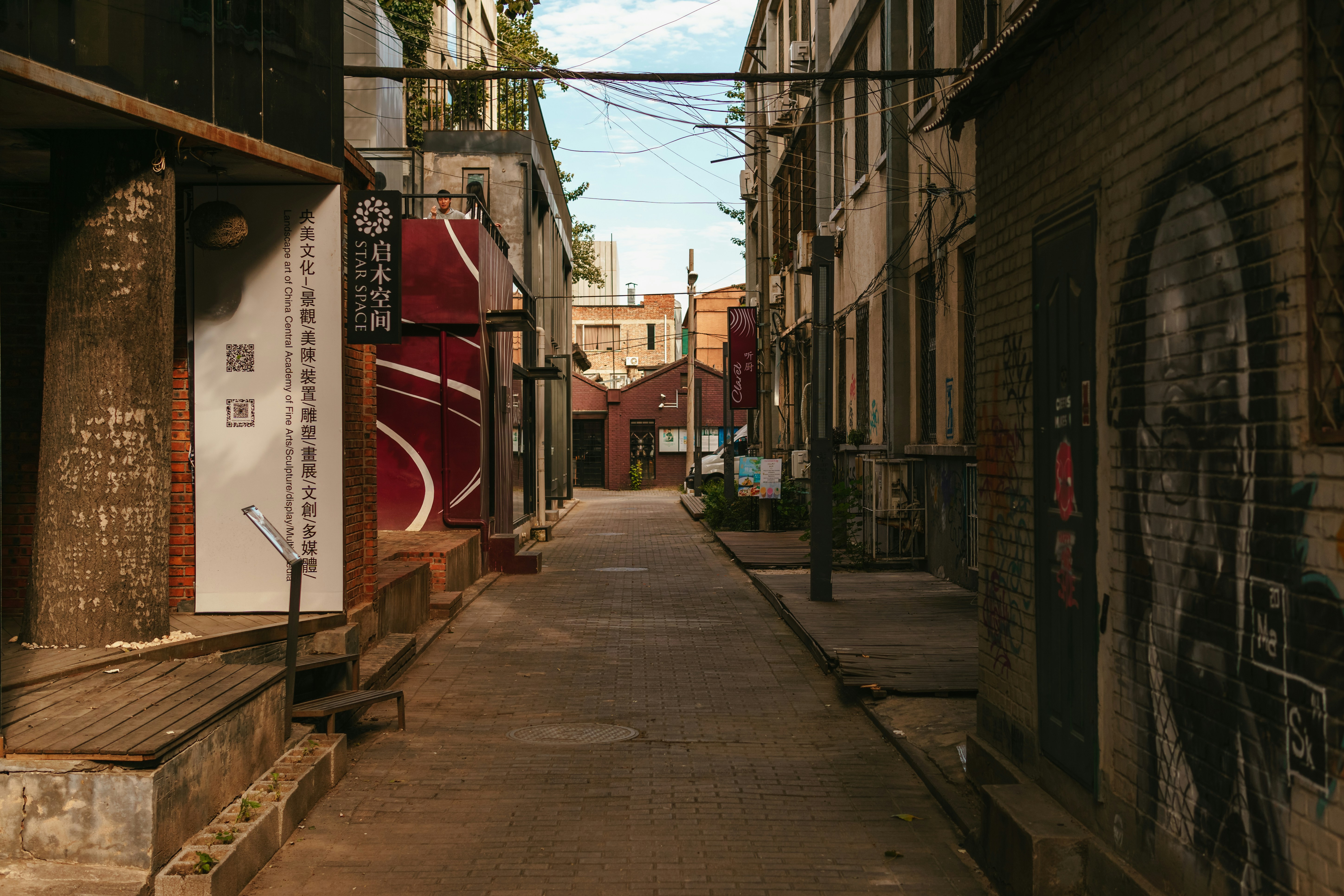 A narrow city street with graffiti on the buildings