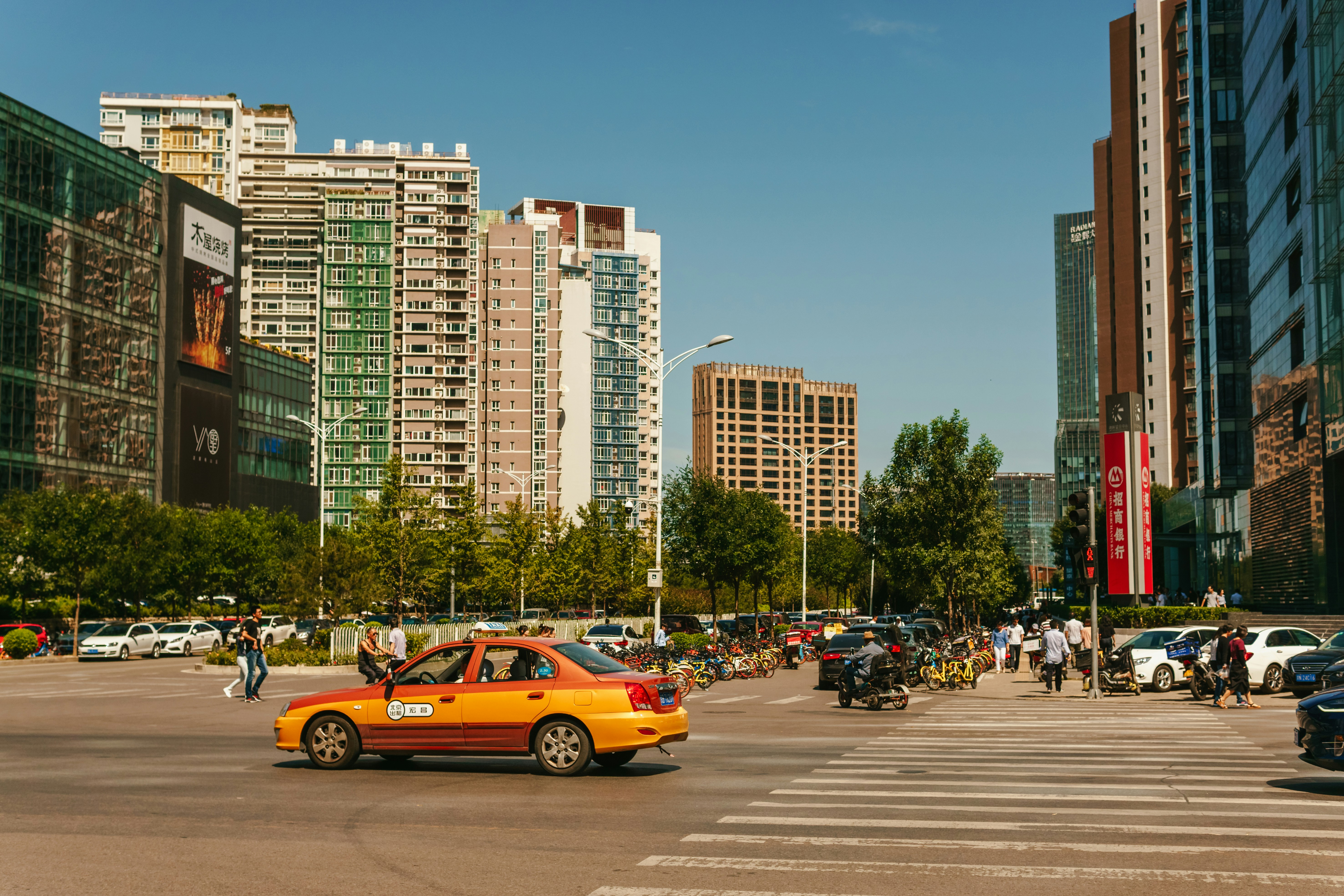 A yellow taxi cab driving down a street next to tall buildings