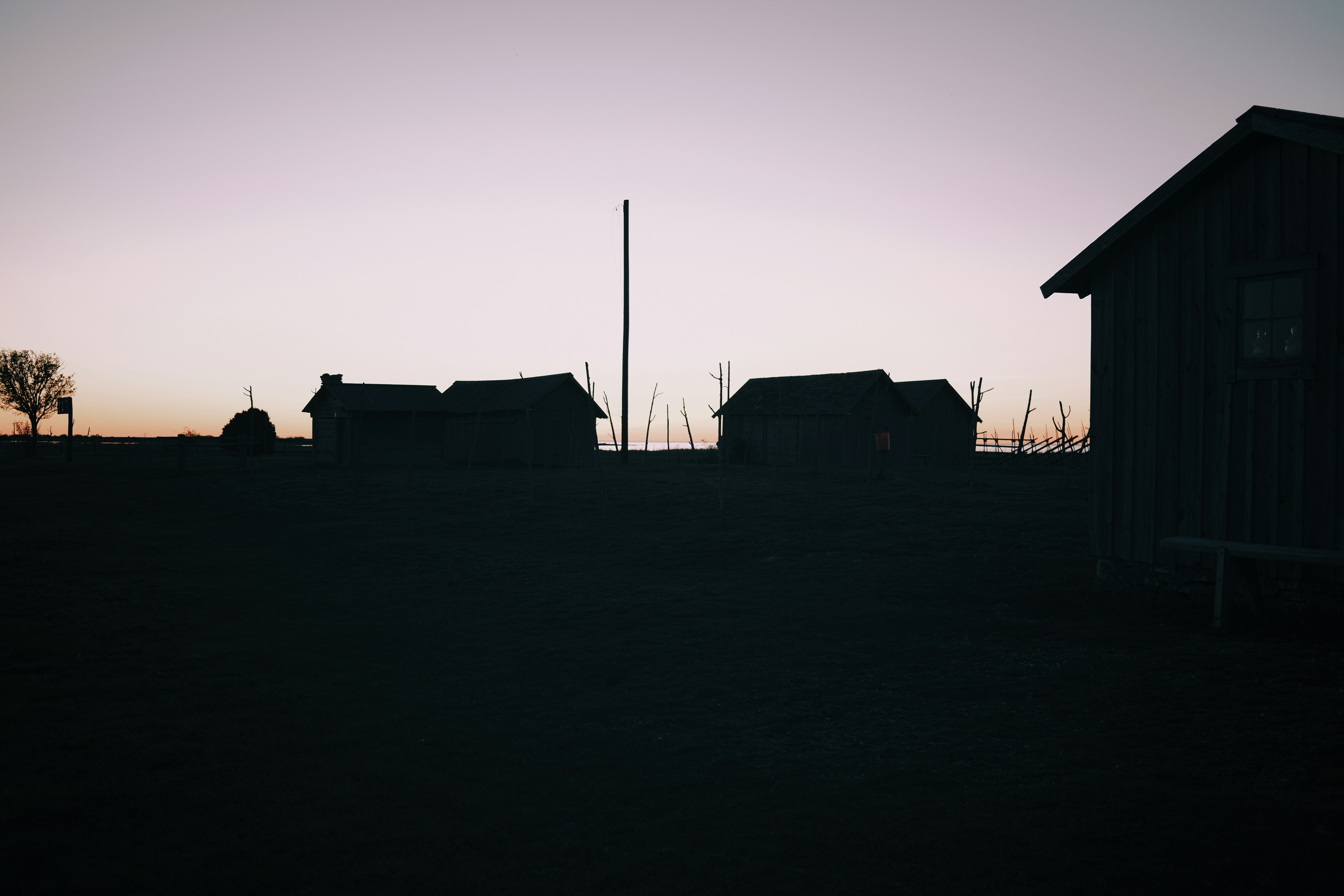 A black and white photo of a barn and a flag pole