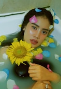 A woman in a bathtub holding a sunflower