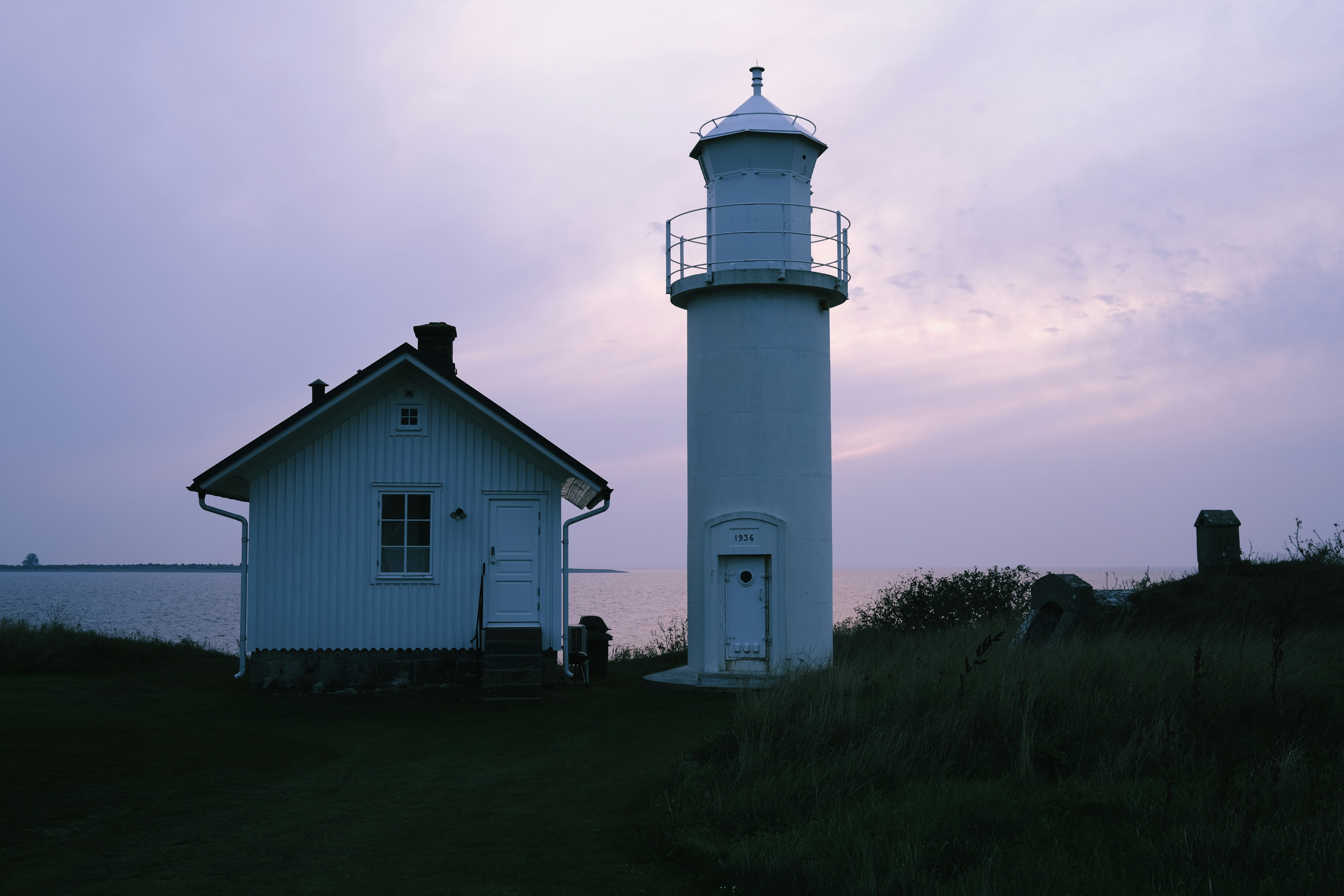 A white house and a white lighthouse on a hill
