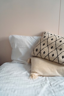 A white bed topped with two pillows and a blanket