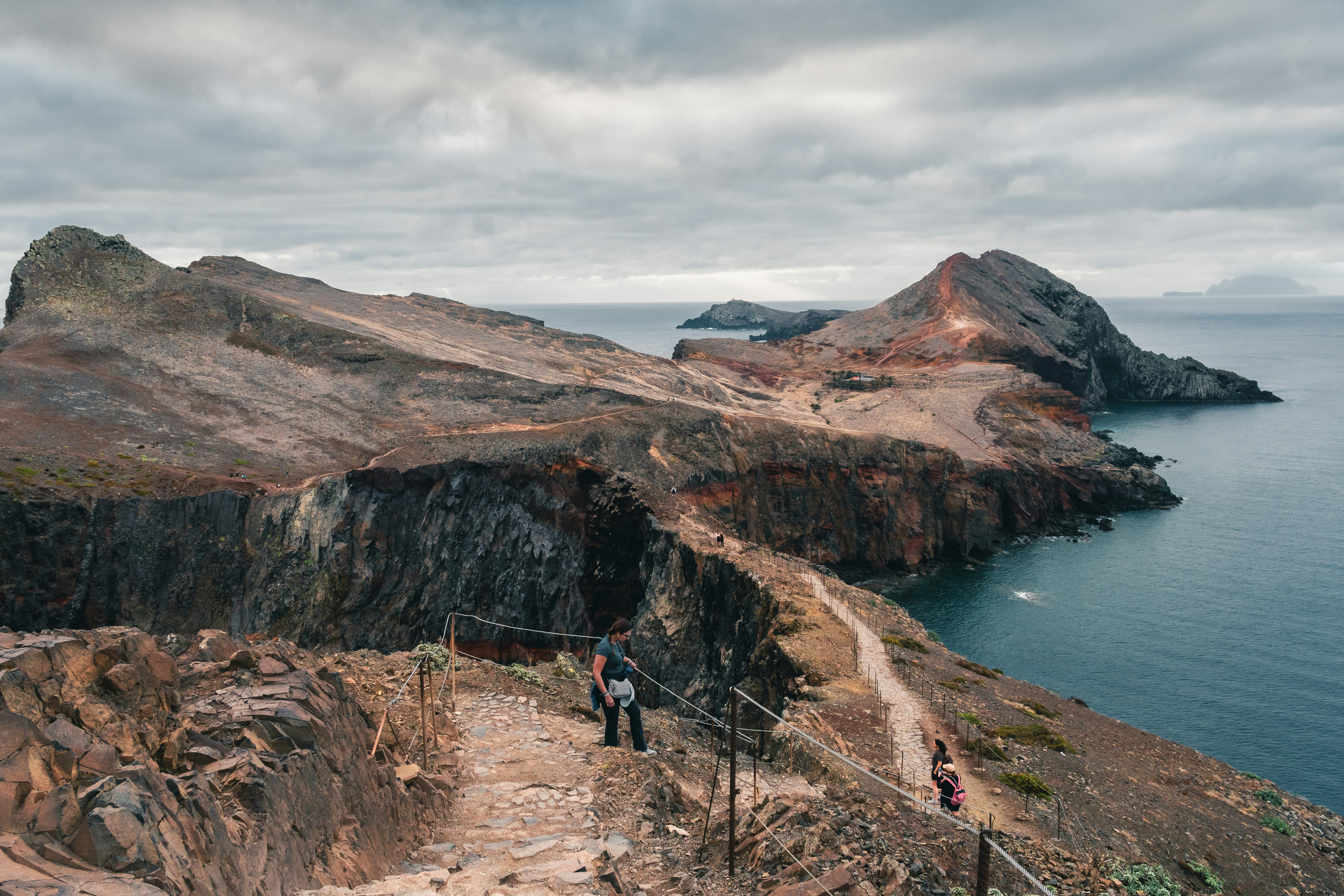 Una pareja de personas subiendo una colina junto a un cuerpo de agua