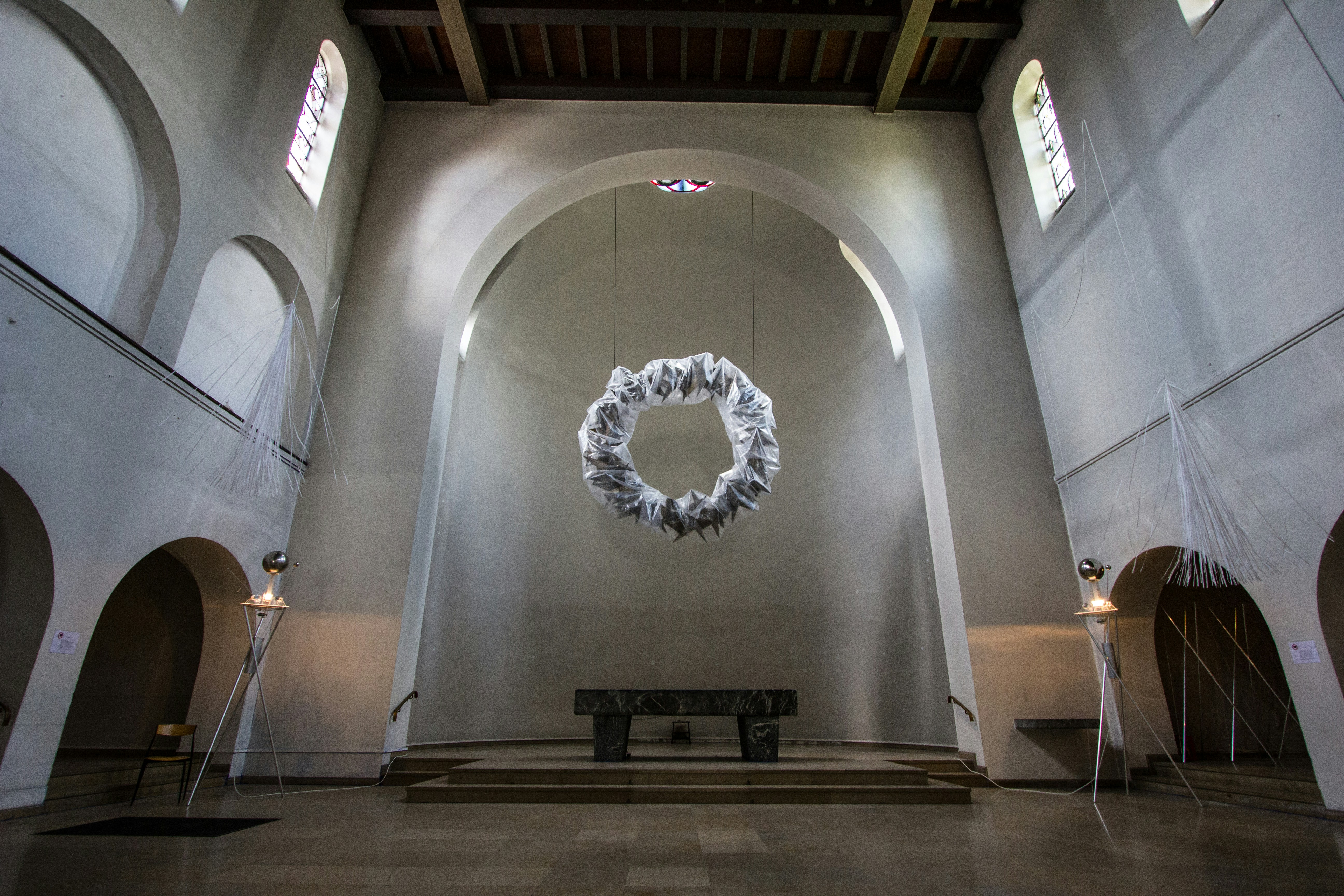 A large room with a bench and a wreath on the wall