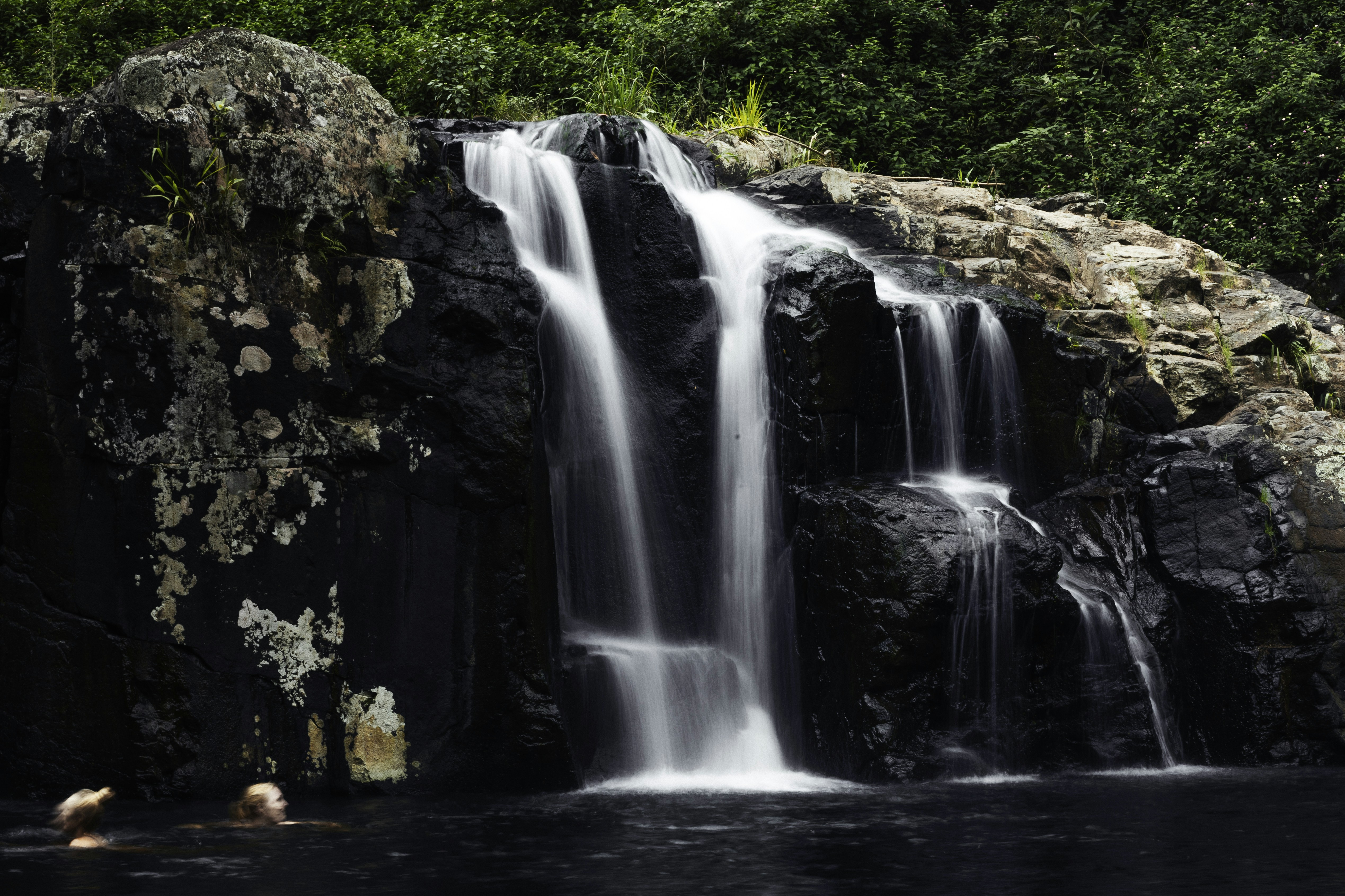 A group of people swimming in a body of water near a waterfall