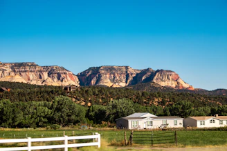 A farm with a white fence and mountains in the background