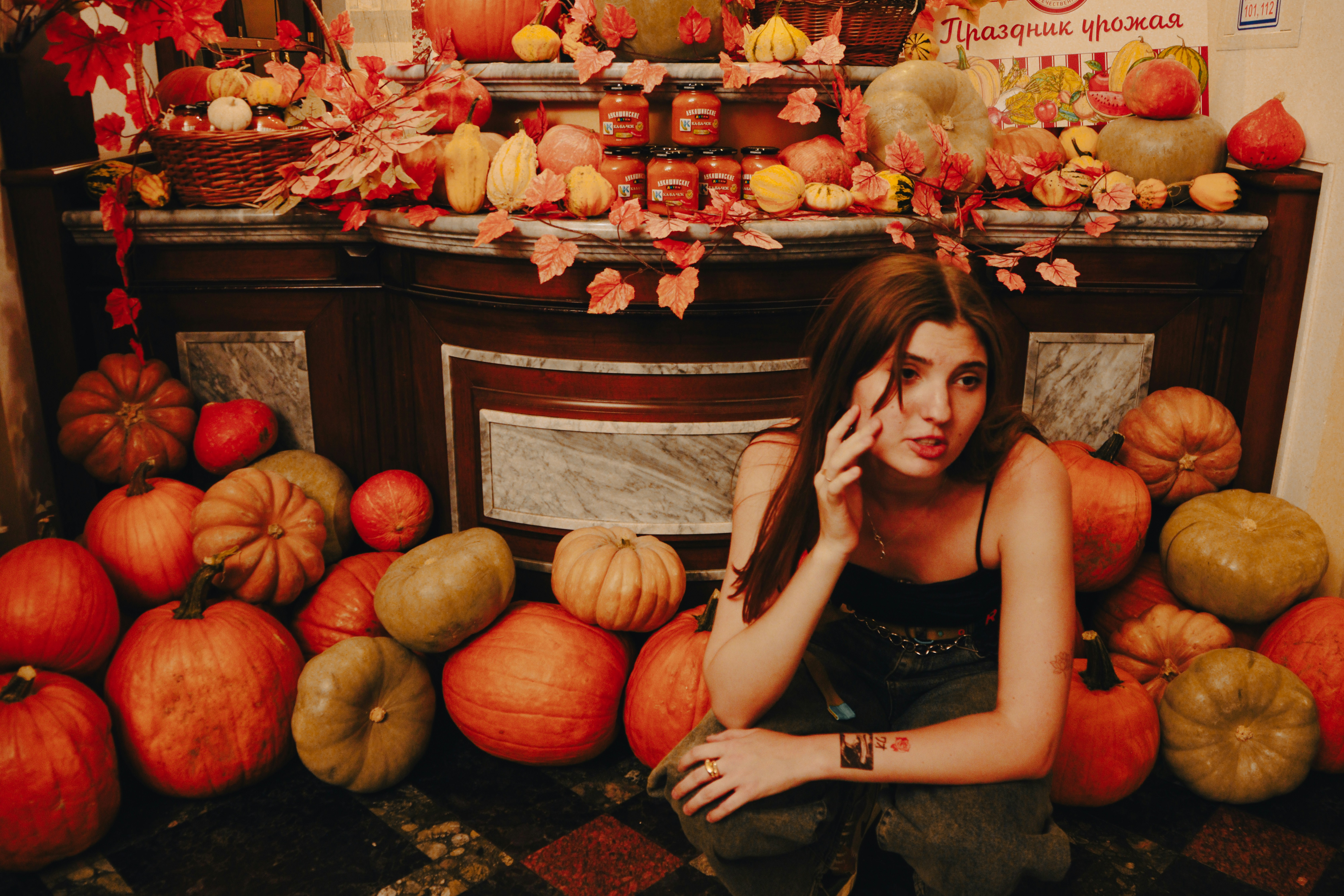 A woman sitting in front of a pile of pumpkins
