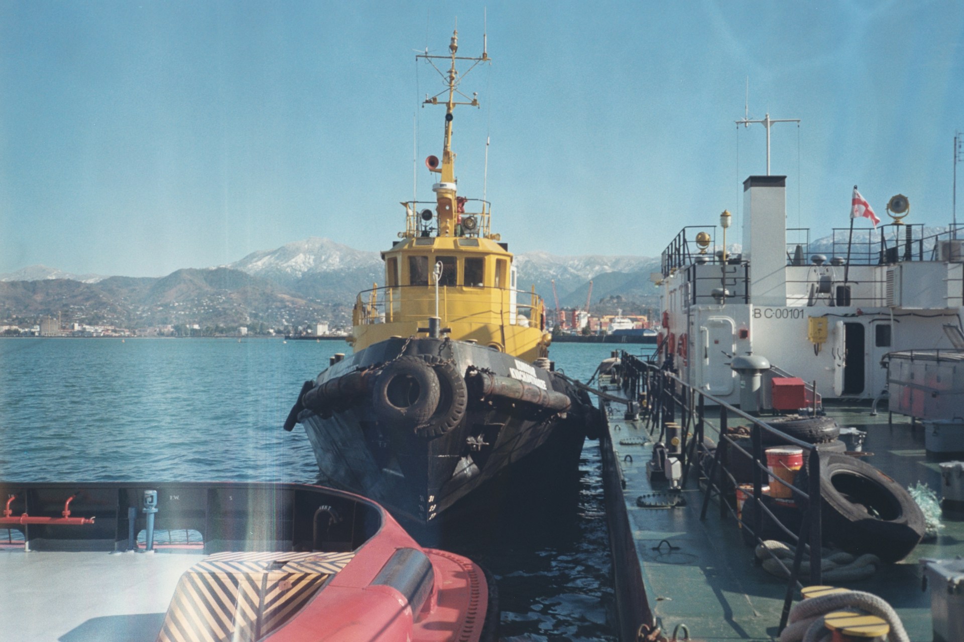 A yellow and black boat and some water and a red car
