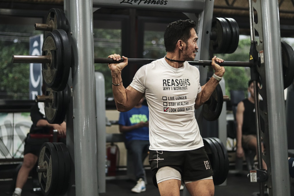 Lifter with a barbell across his shoulders setting up for a squat in a busy gym