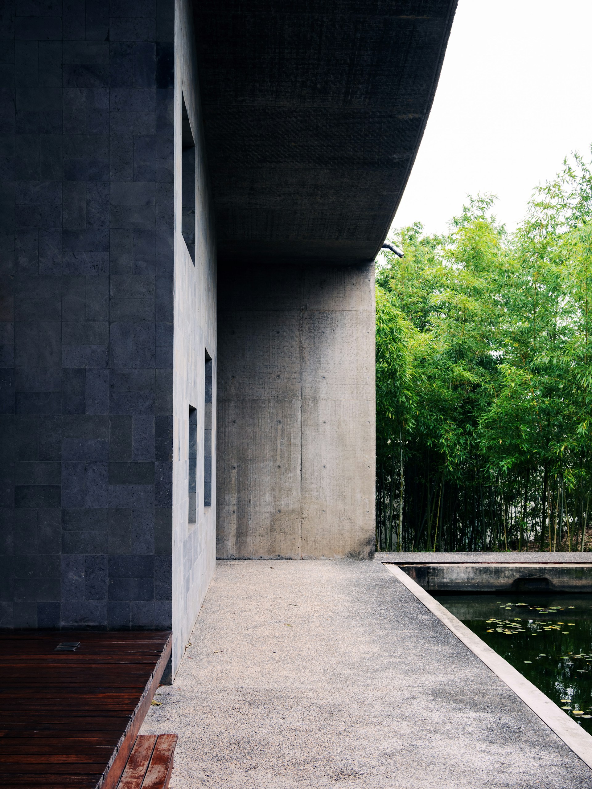 A walkway leading to a building with a pond in front of it