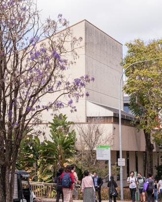 A group of people walking down a sidewalk next to a building