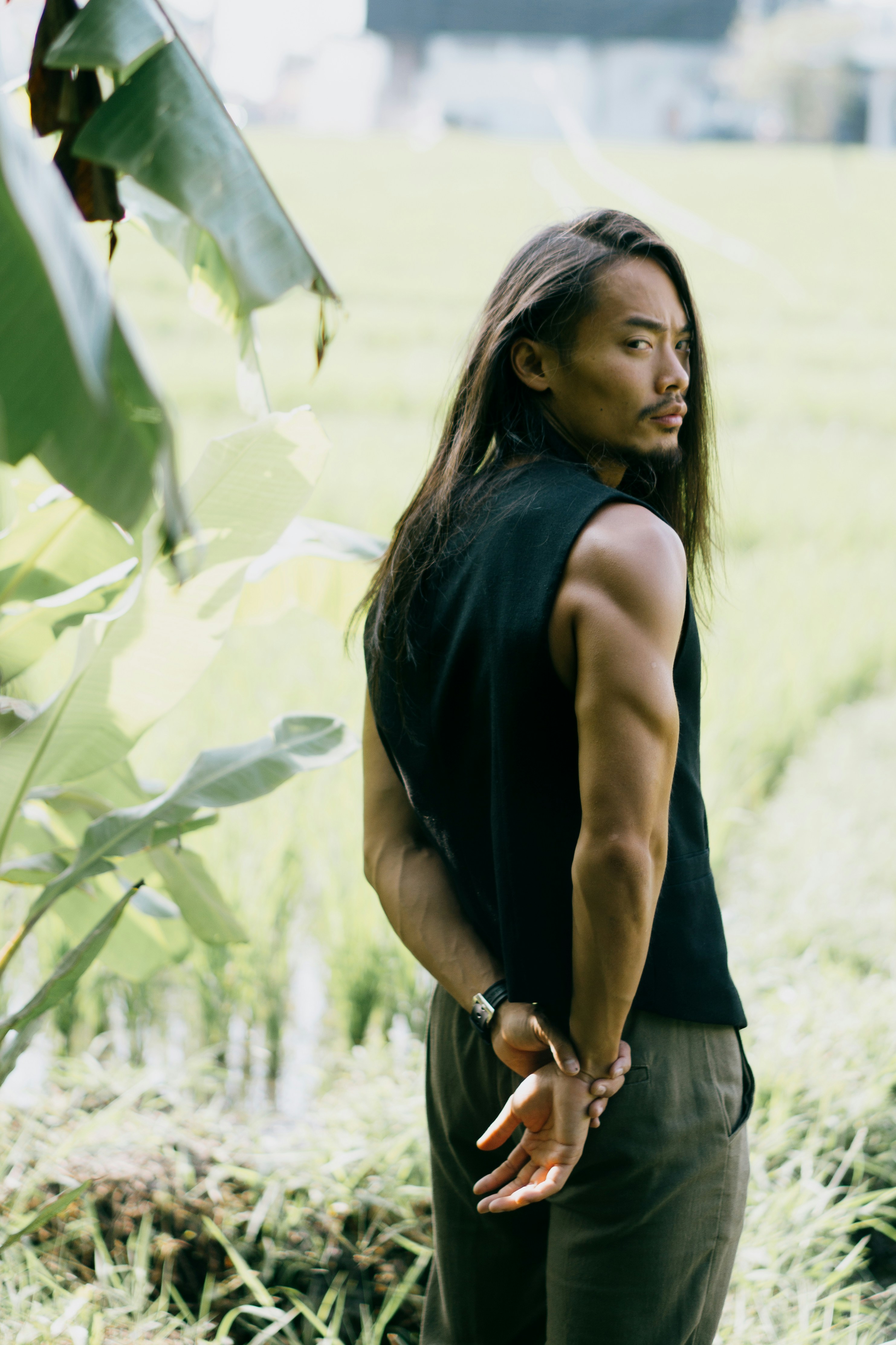 A man with long hair standing in a field