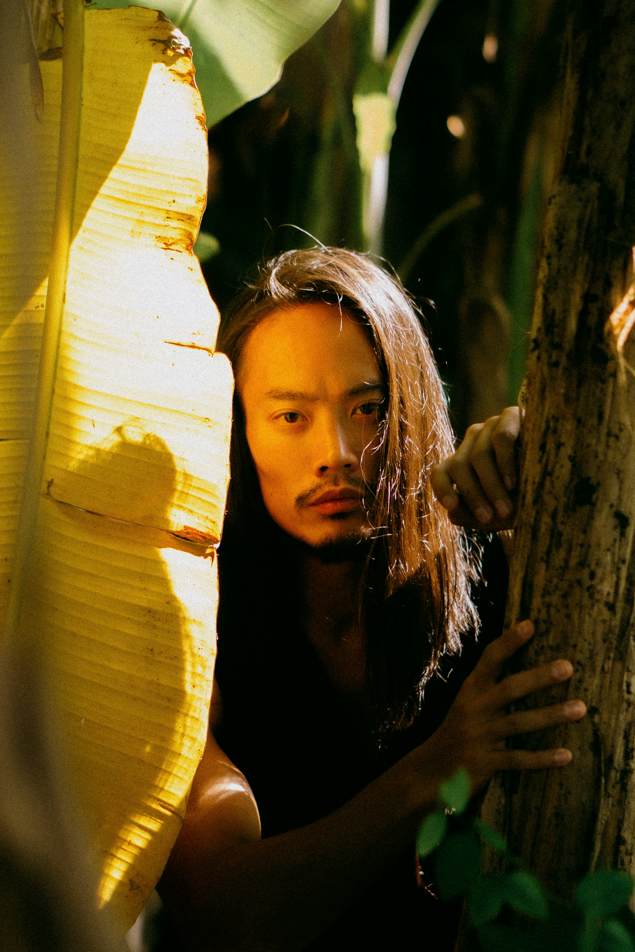 A man standing next to a banana tree
