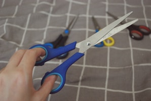 A person holding a pair of scissors on a bed
