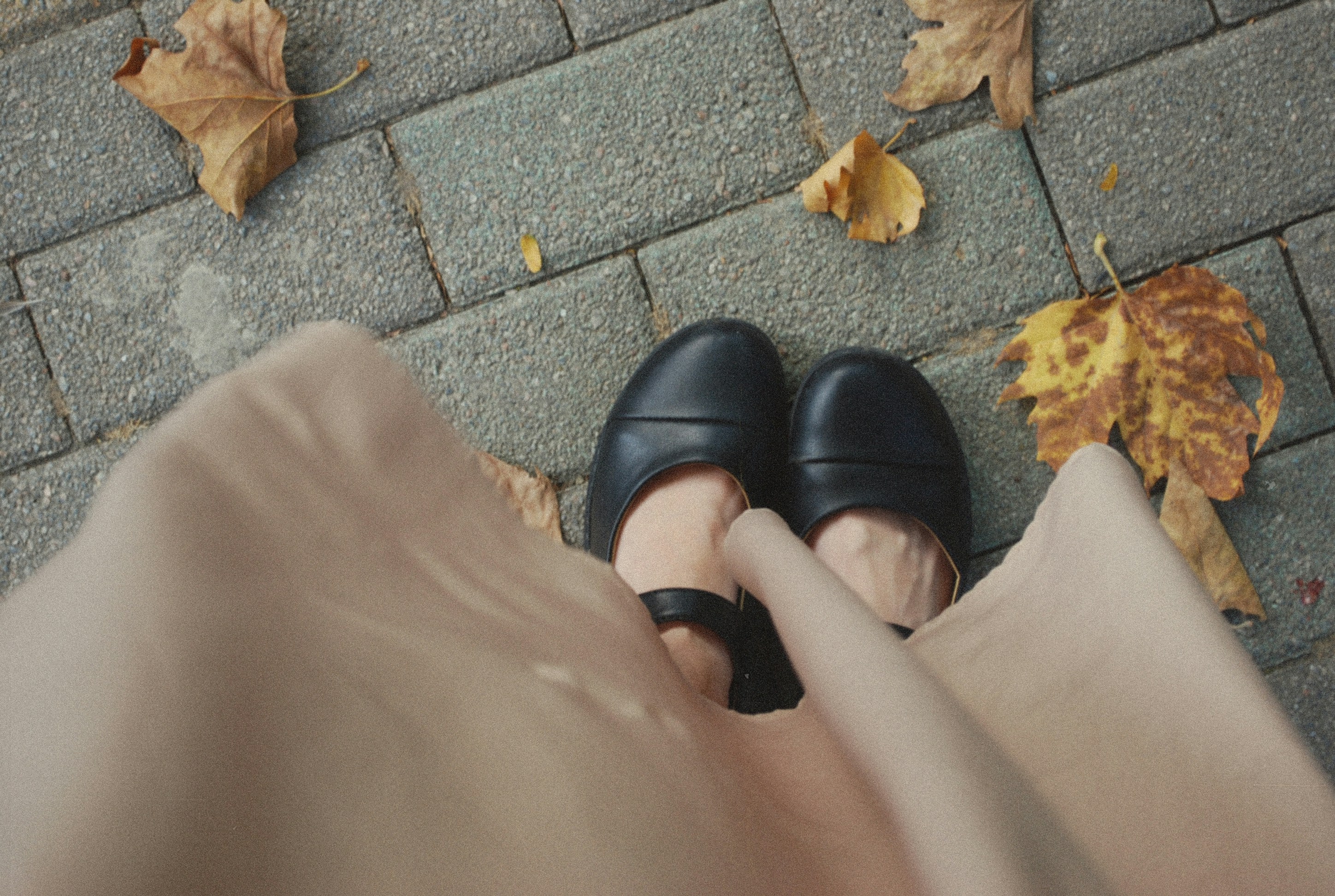 A person wearing black shoes standing on a sidewalk