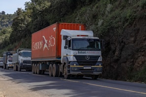 A truck driving down a road next to a mountain