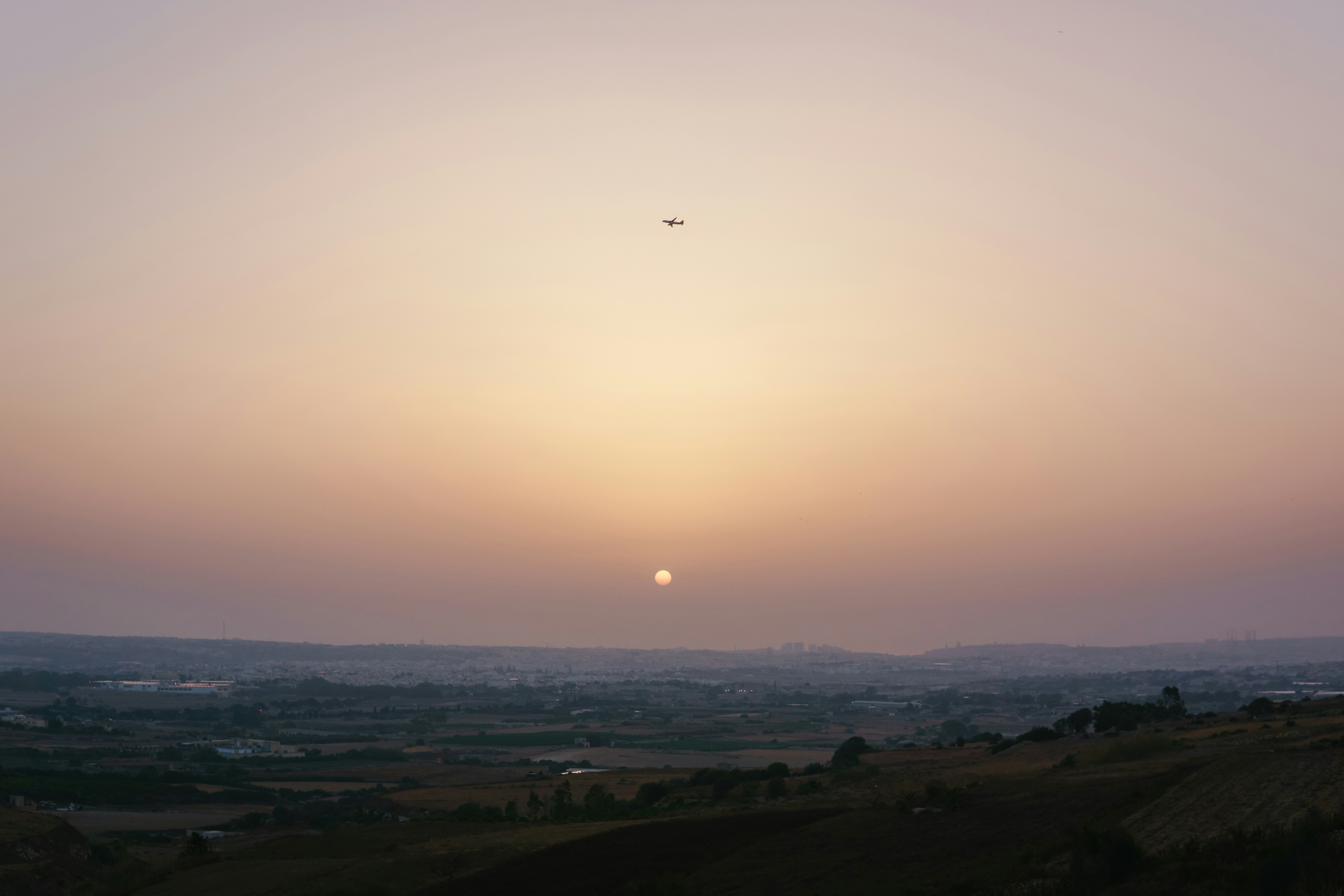 The sun is setting over a hilly area