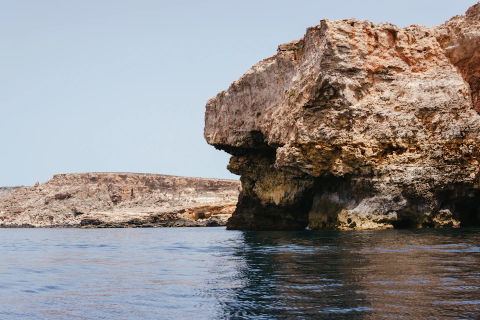 Rocky cliff face features large jagged rock formation on right side and smaller one left