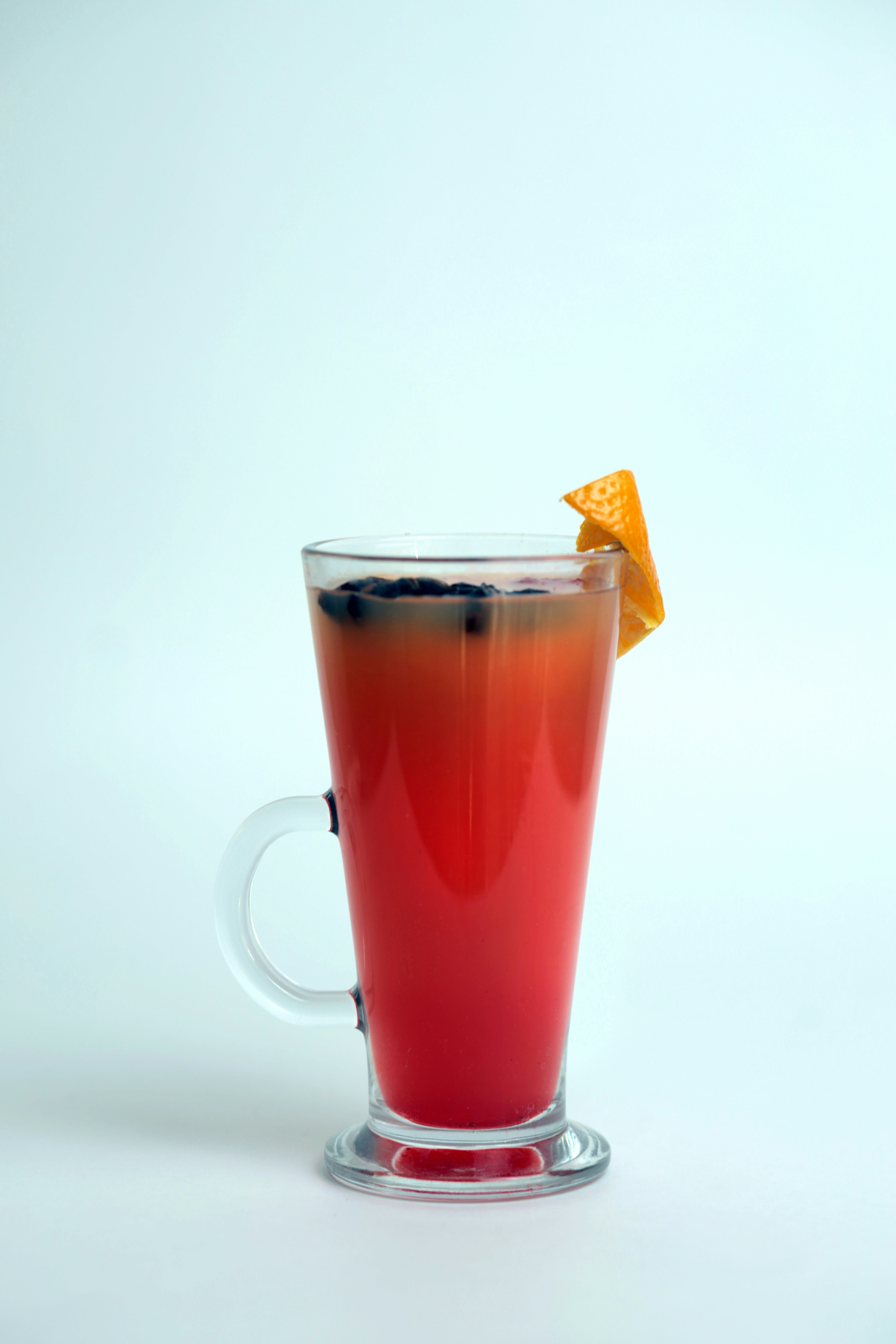 A red drink with a slice of orange on top of it