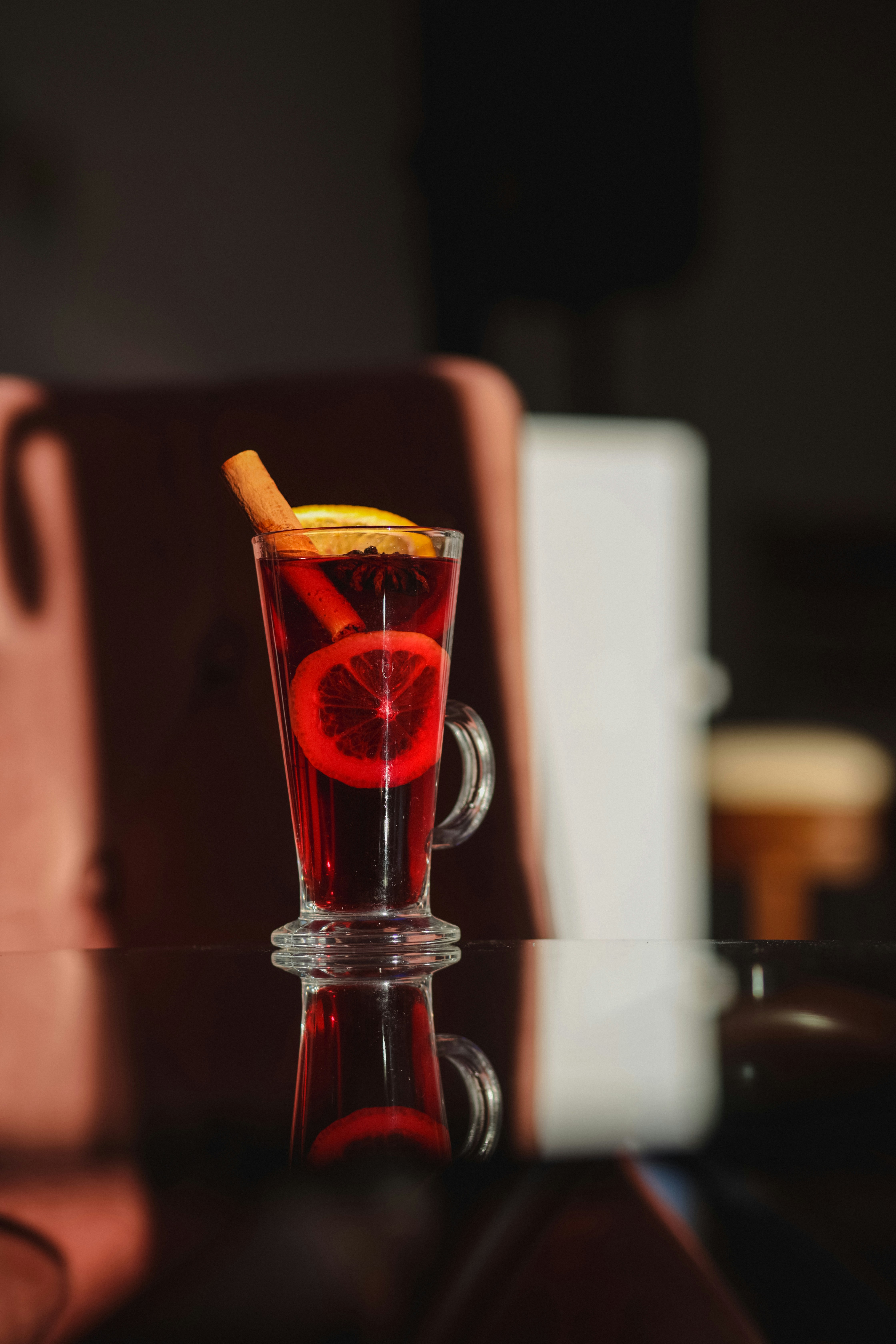 A red drink with a slice of orange on top of it