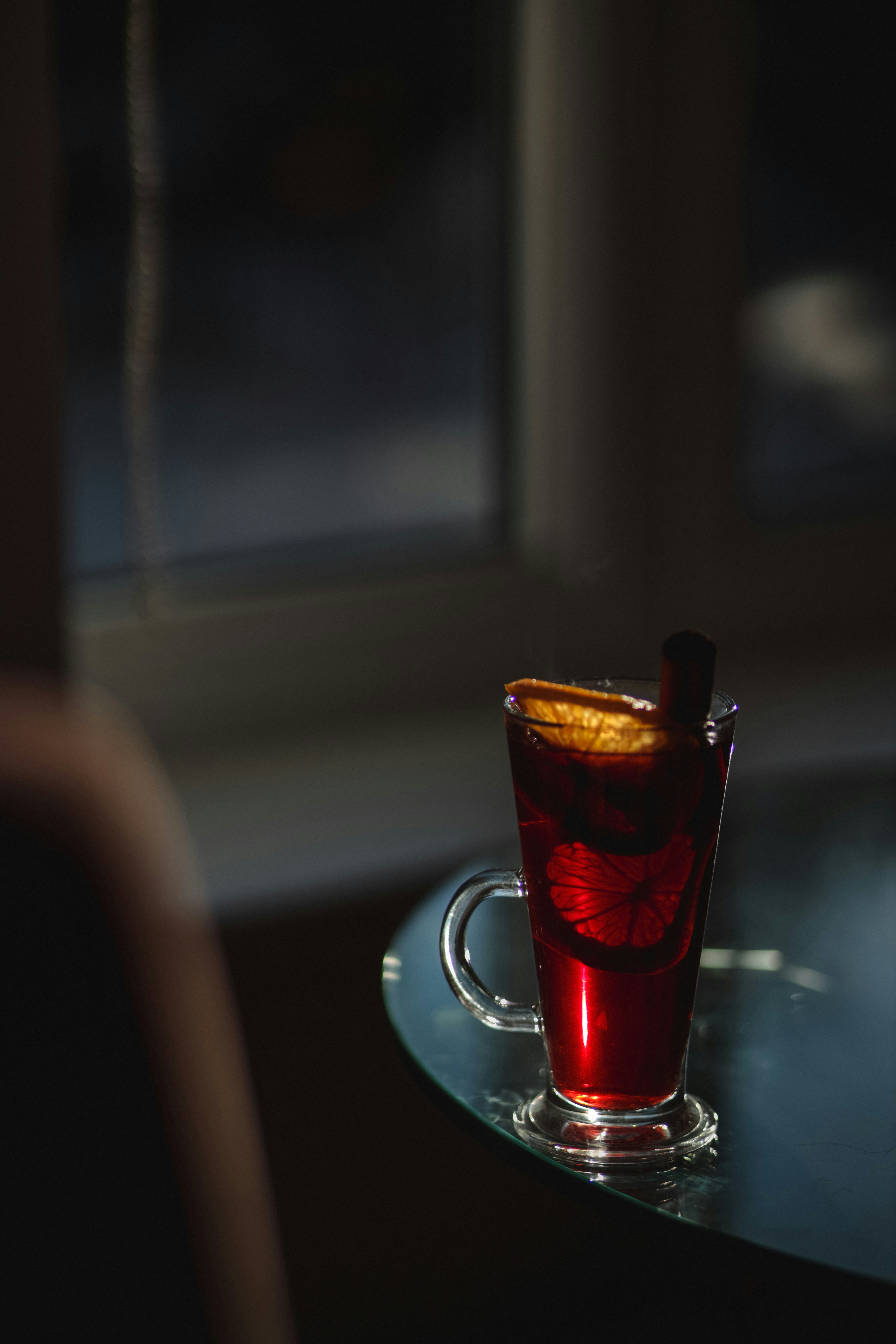 A glass of drink sitting on a table next to a window