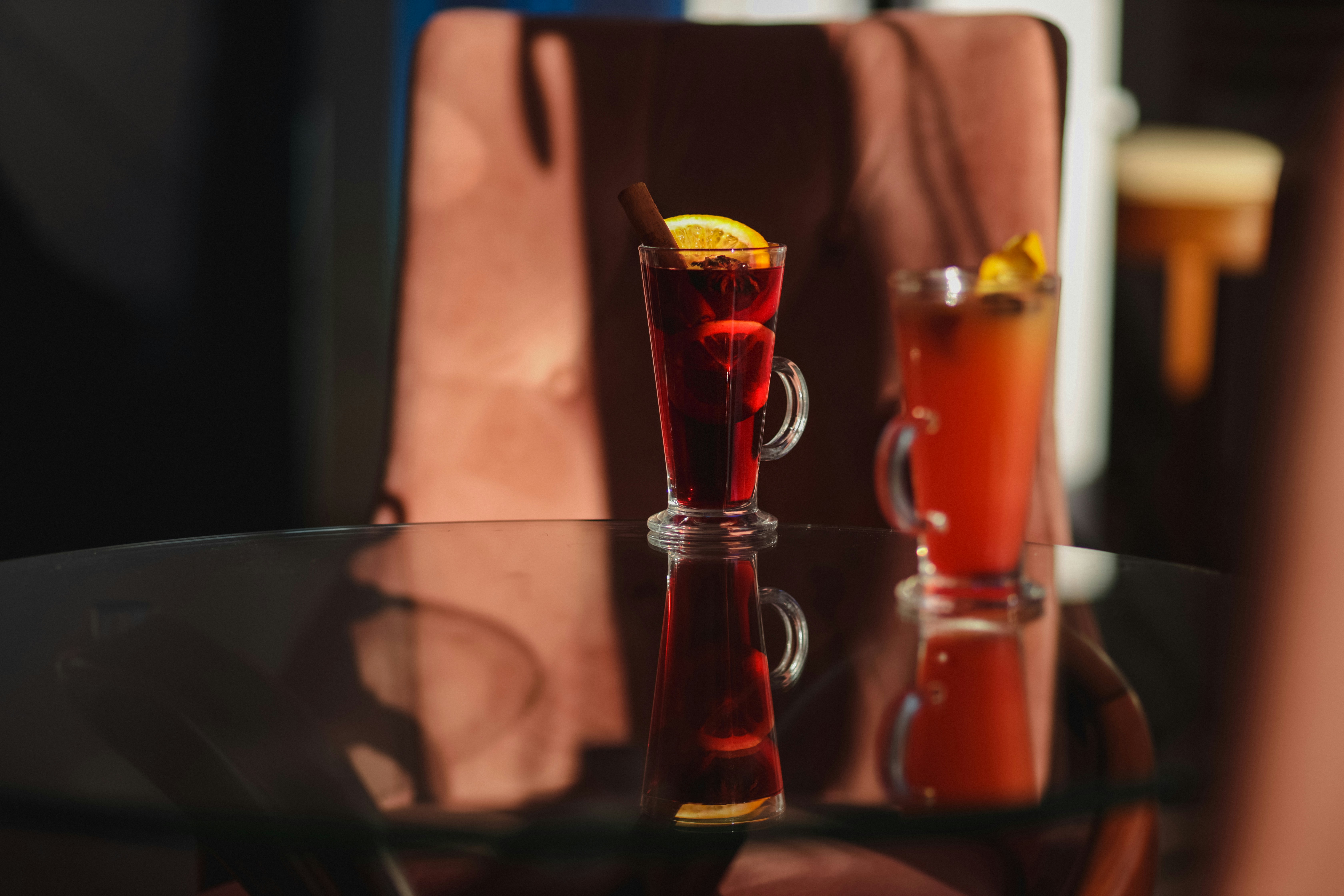 A glass table topped with two glasses filled with liquid