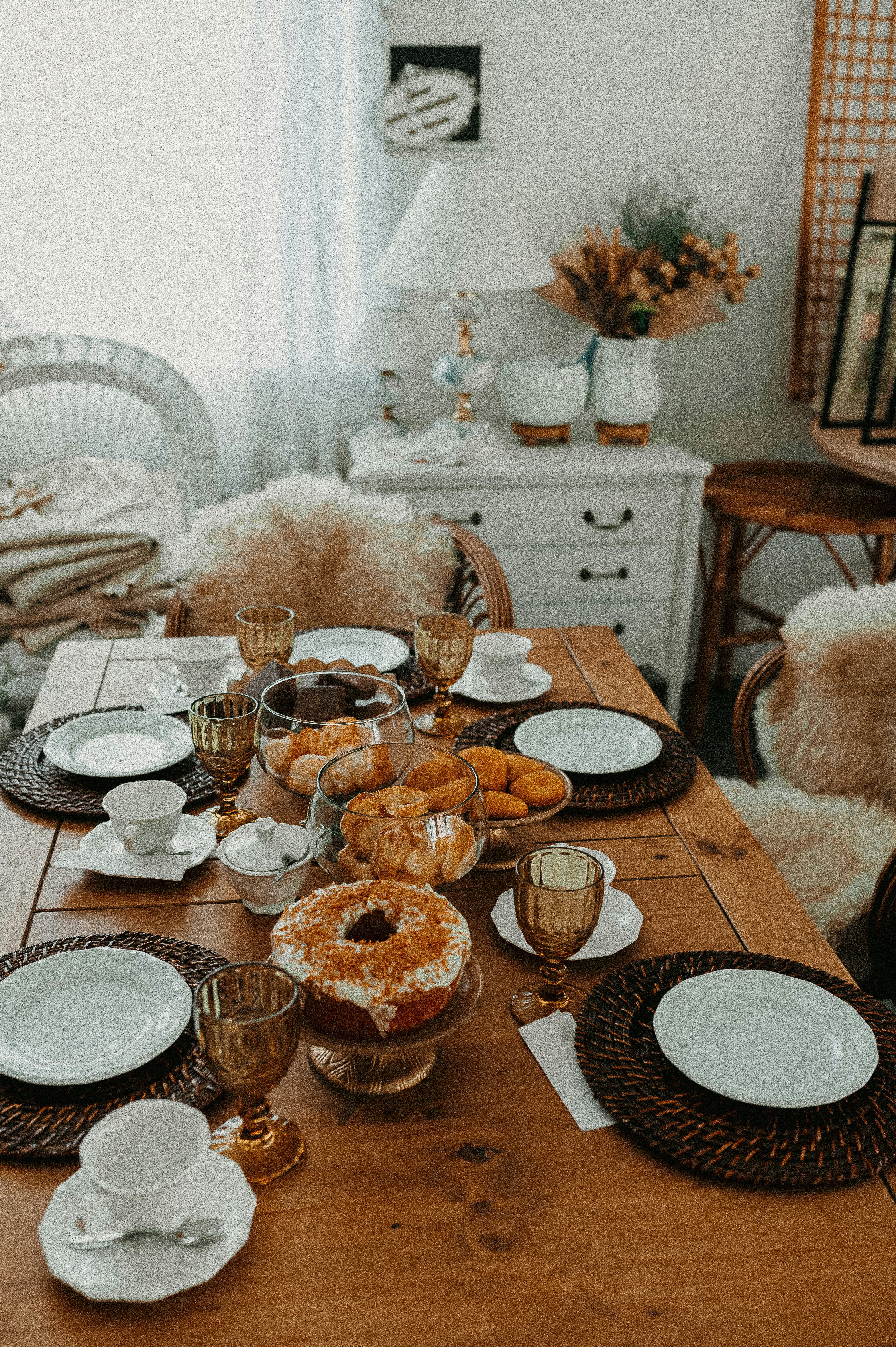 A wooden table topped with plates and bowls filled with donuts