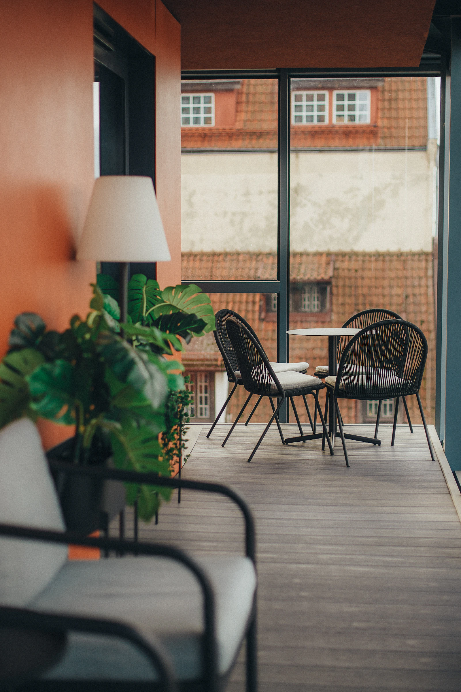 A balcony with chairs and a table with a lamp on it
