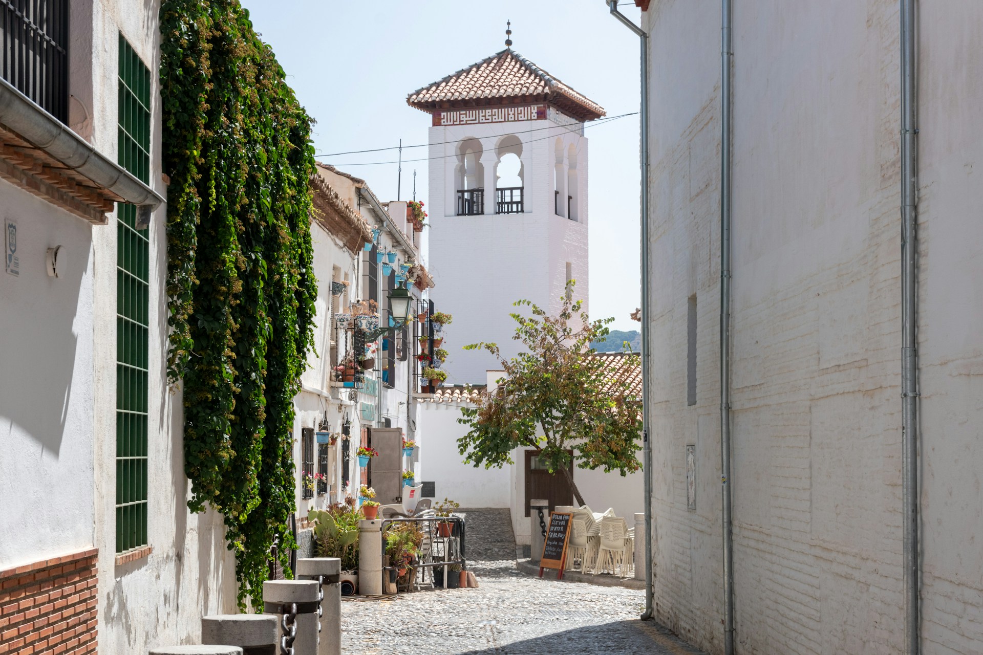A narrow street with a clock tower in the background