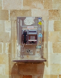 An old fashioned pay phone on a brick wall