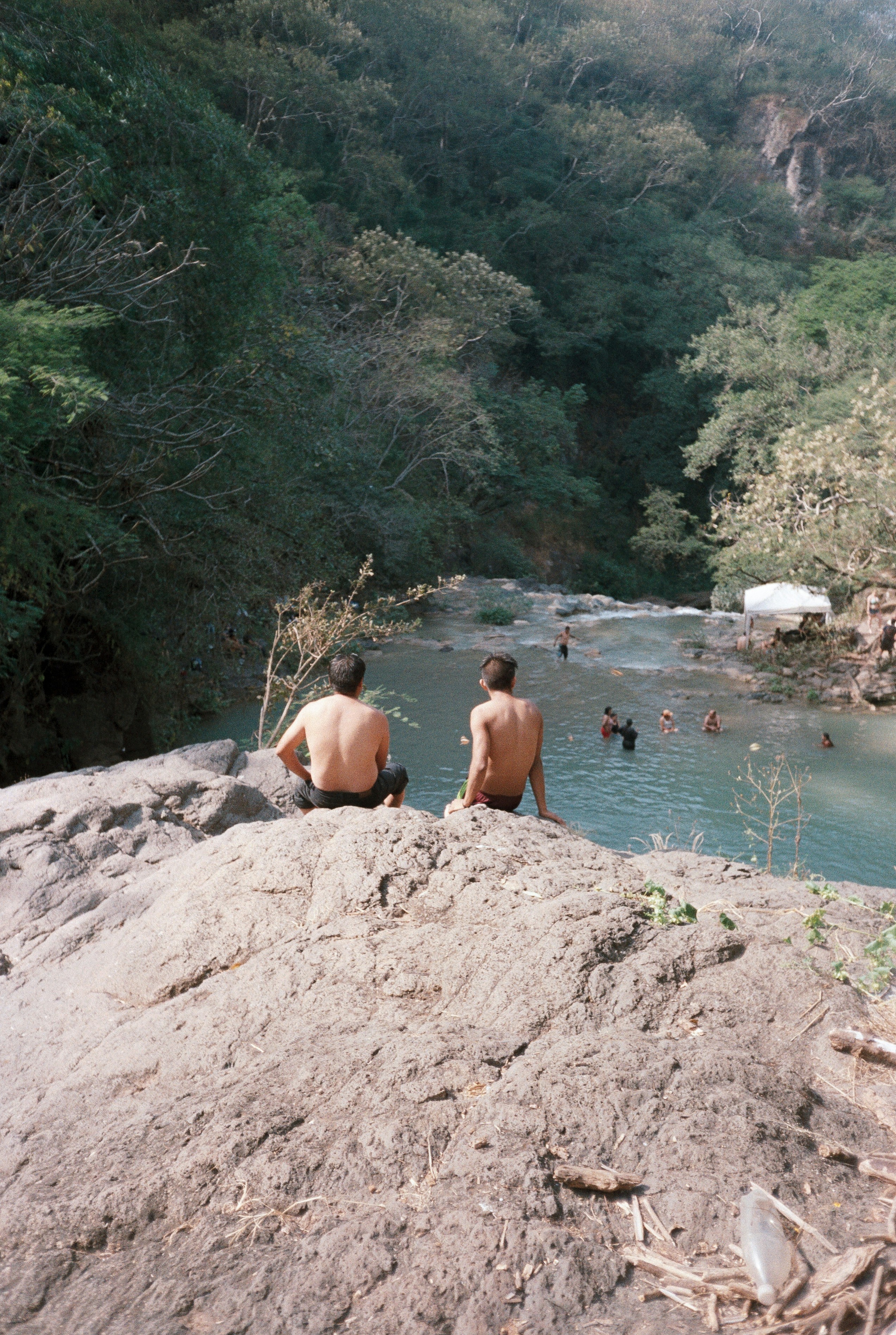 A couple of people sitting on top of a cliff next to a river photo ...