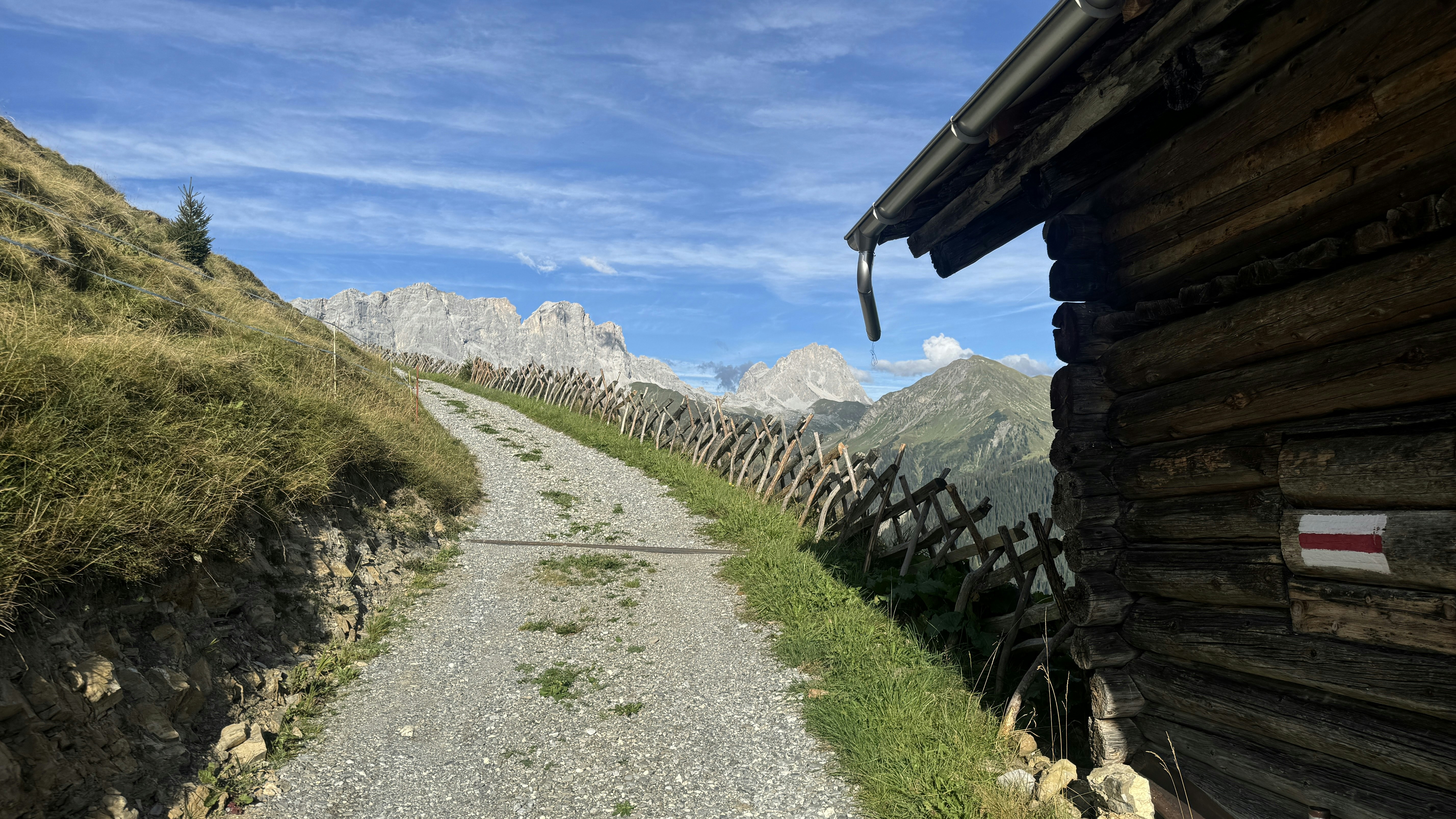 A dirt road next to a wooden cabin