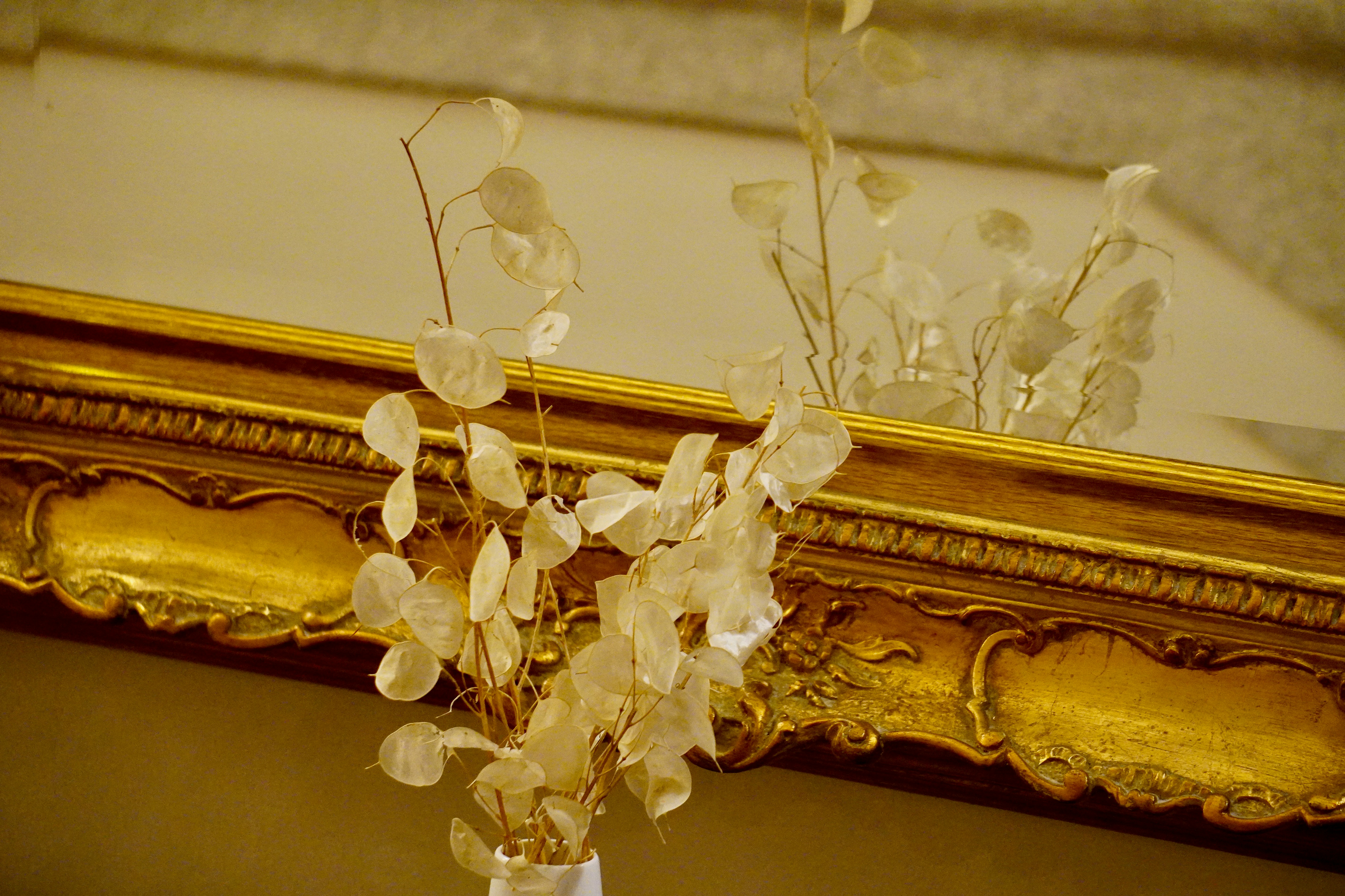 A vase filled with flowers sitting in front of a mirror
