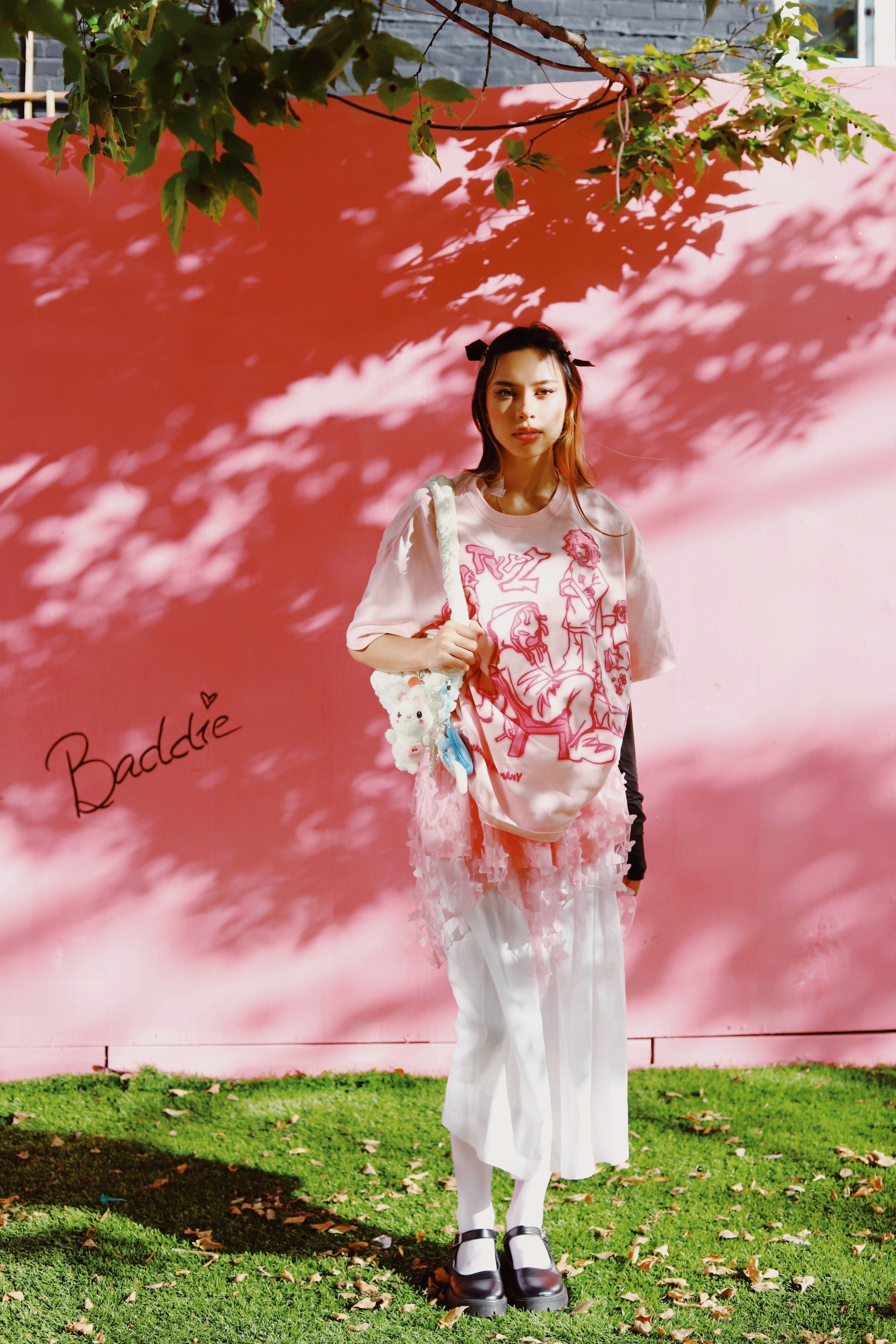 A woman standing in front of a pink wall