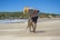 A man with a hat and a dog on a beach
