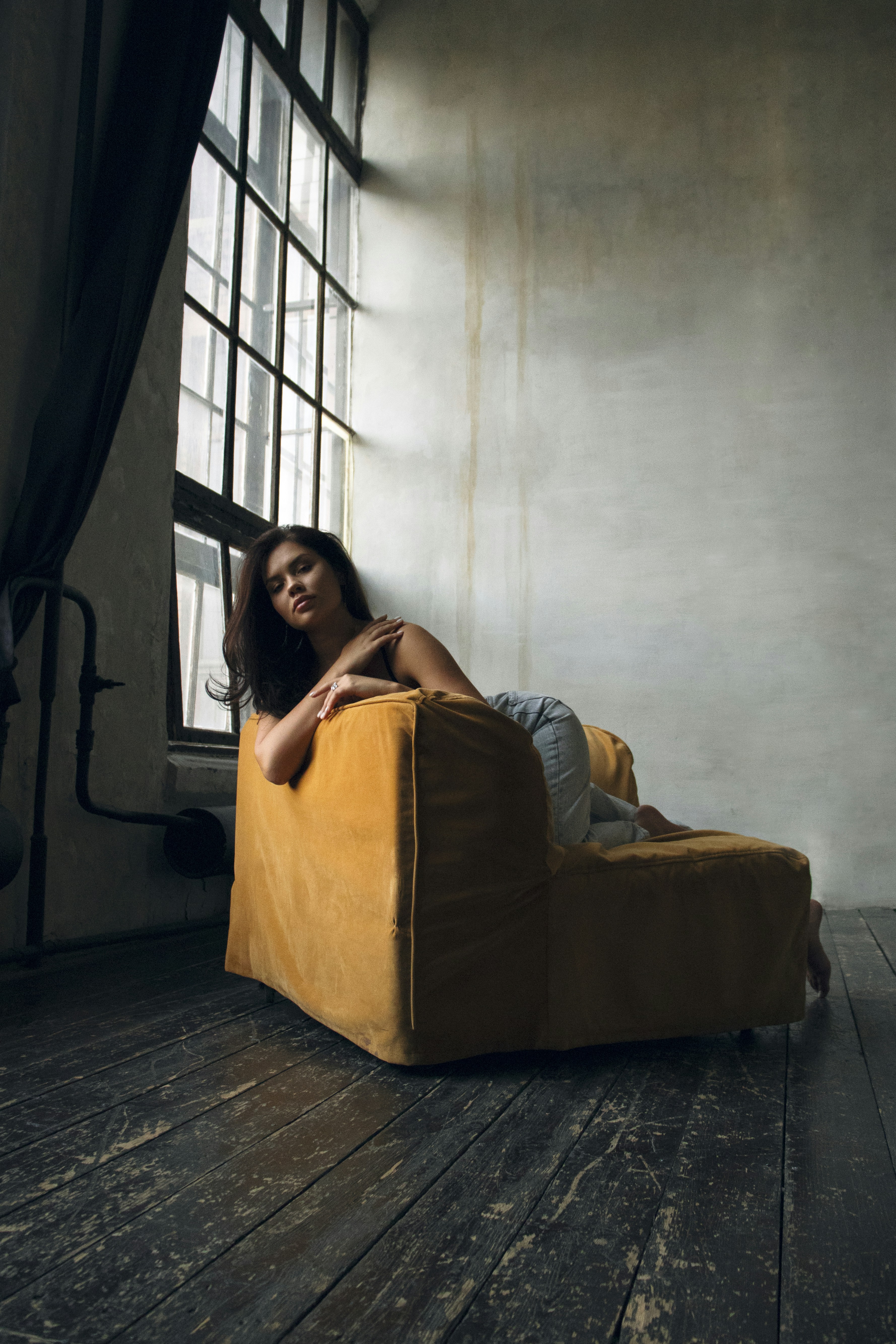 A woman laying on a yellow chair in a dark room