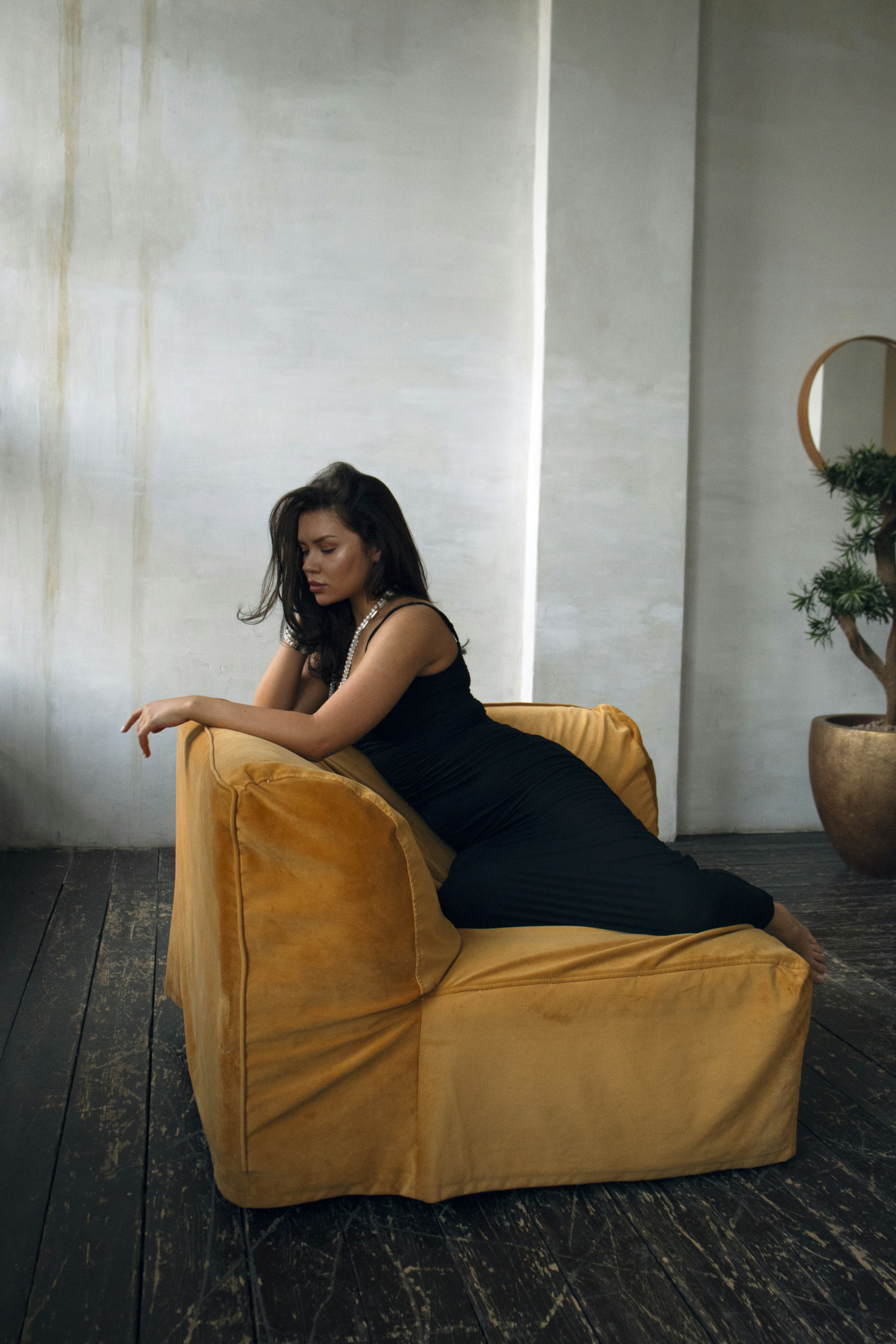 A woman in a black dress sitting on a yellow chair