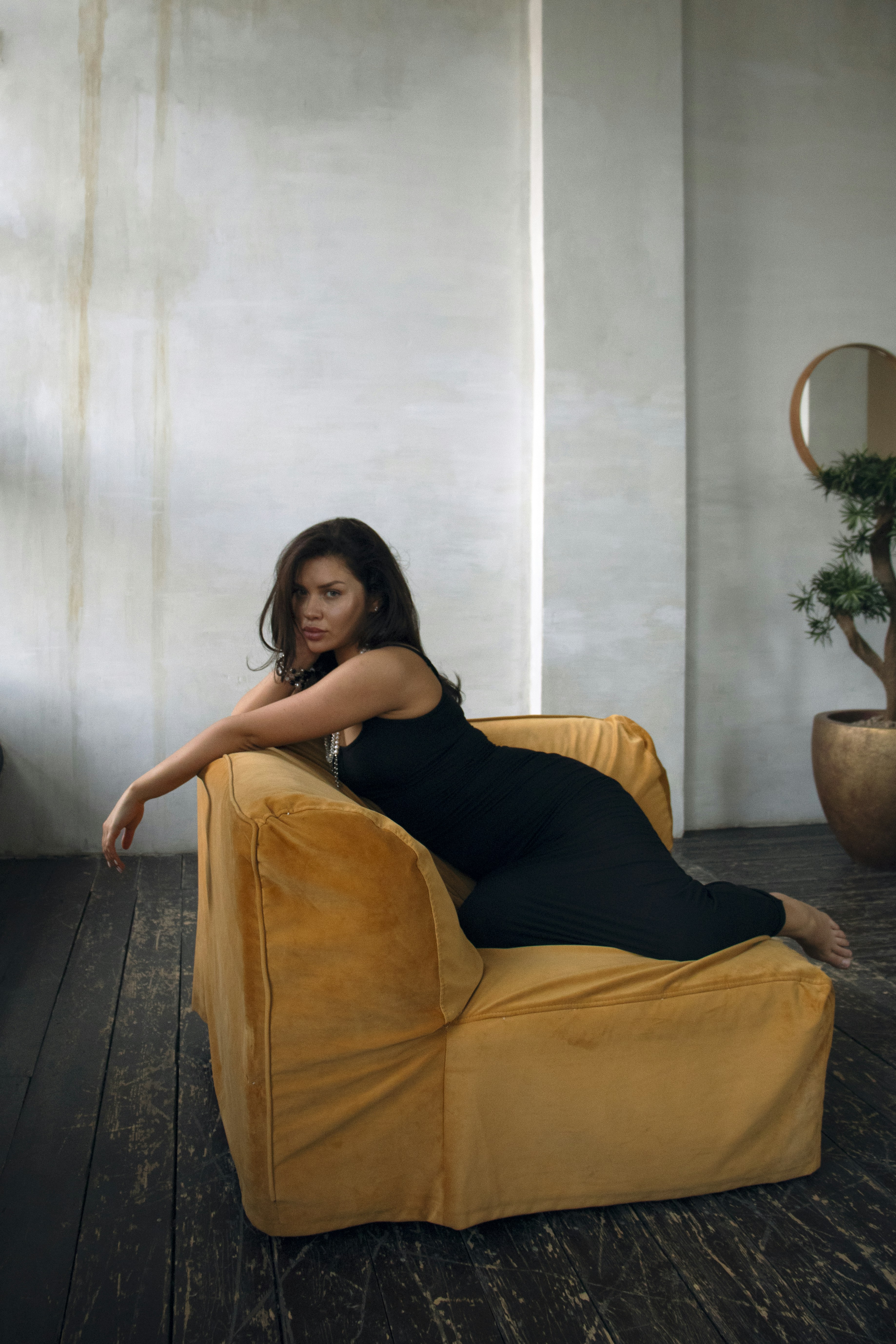 A woman in a black dress sitting on a yellow chair
