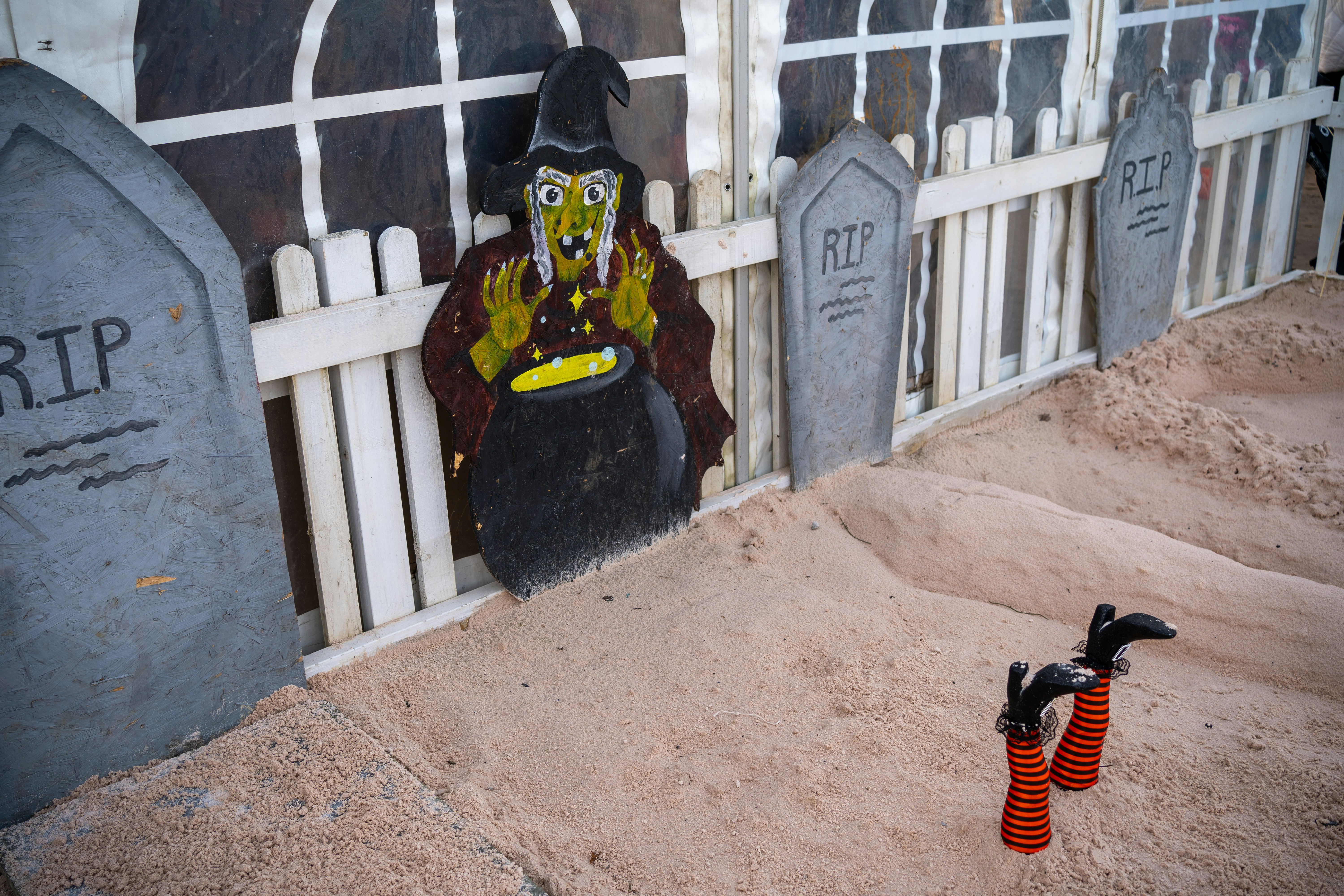 A halloween decoration of a scarecrow sitting in front of a cemetery