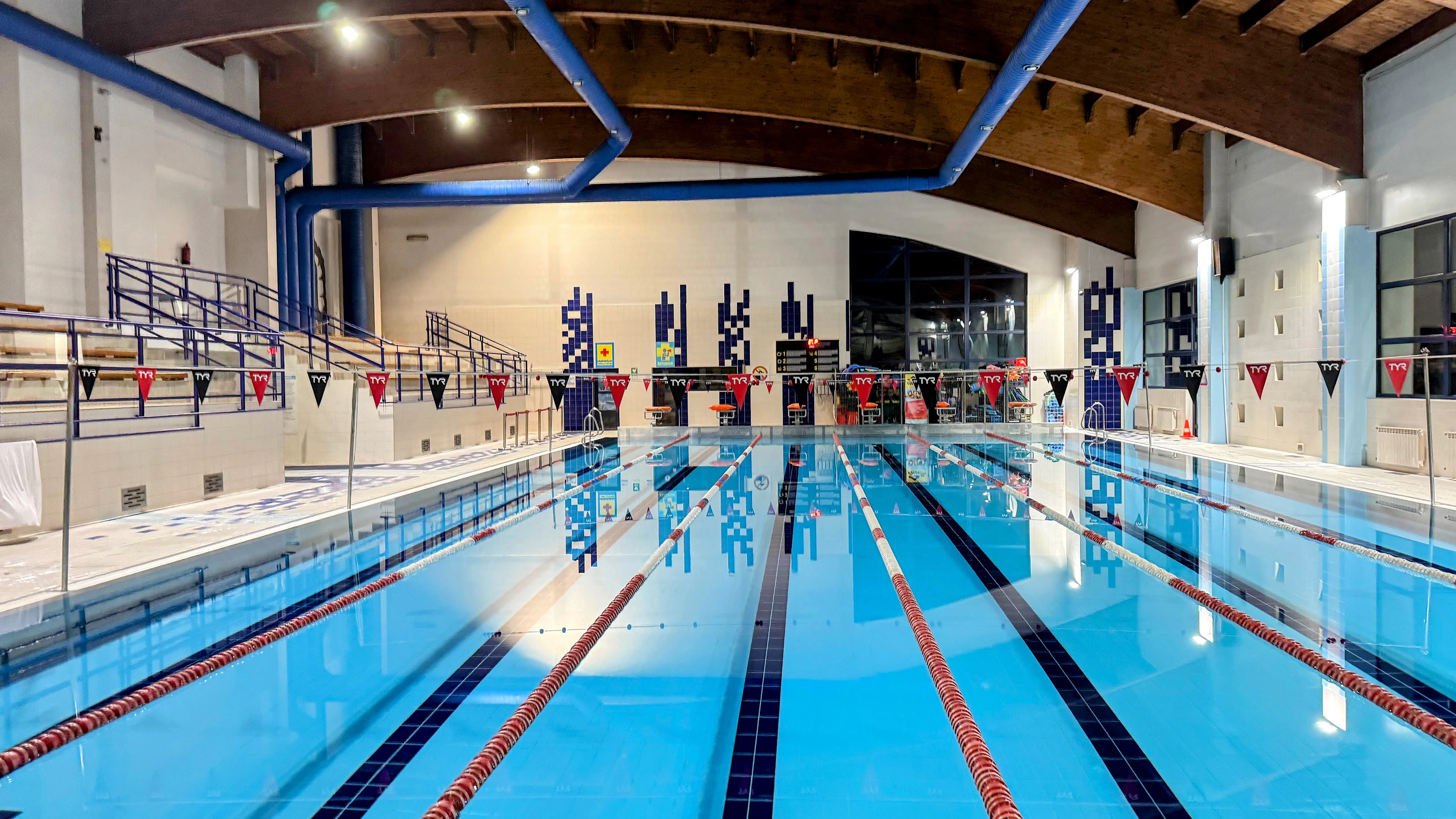 Empty indoor swimming pool with lane ropes and starting blocks
