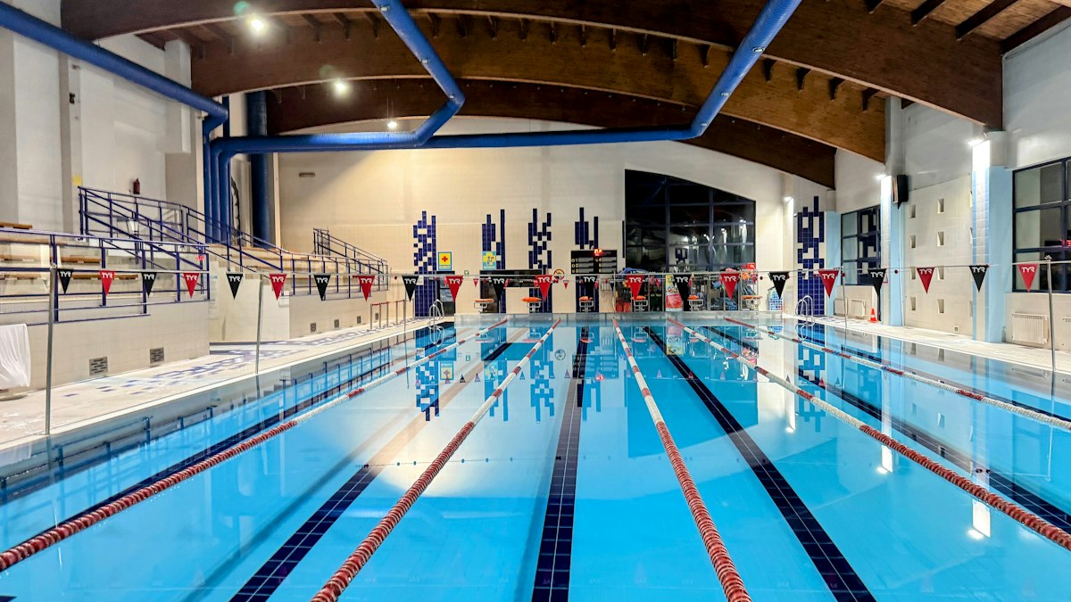 Bassin de natation couvert avec lignes d'eau, plots de départ et gradins