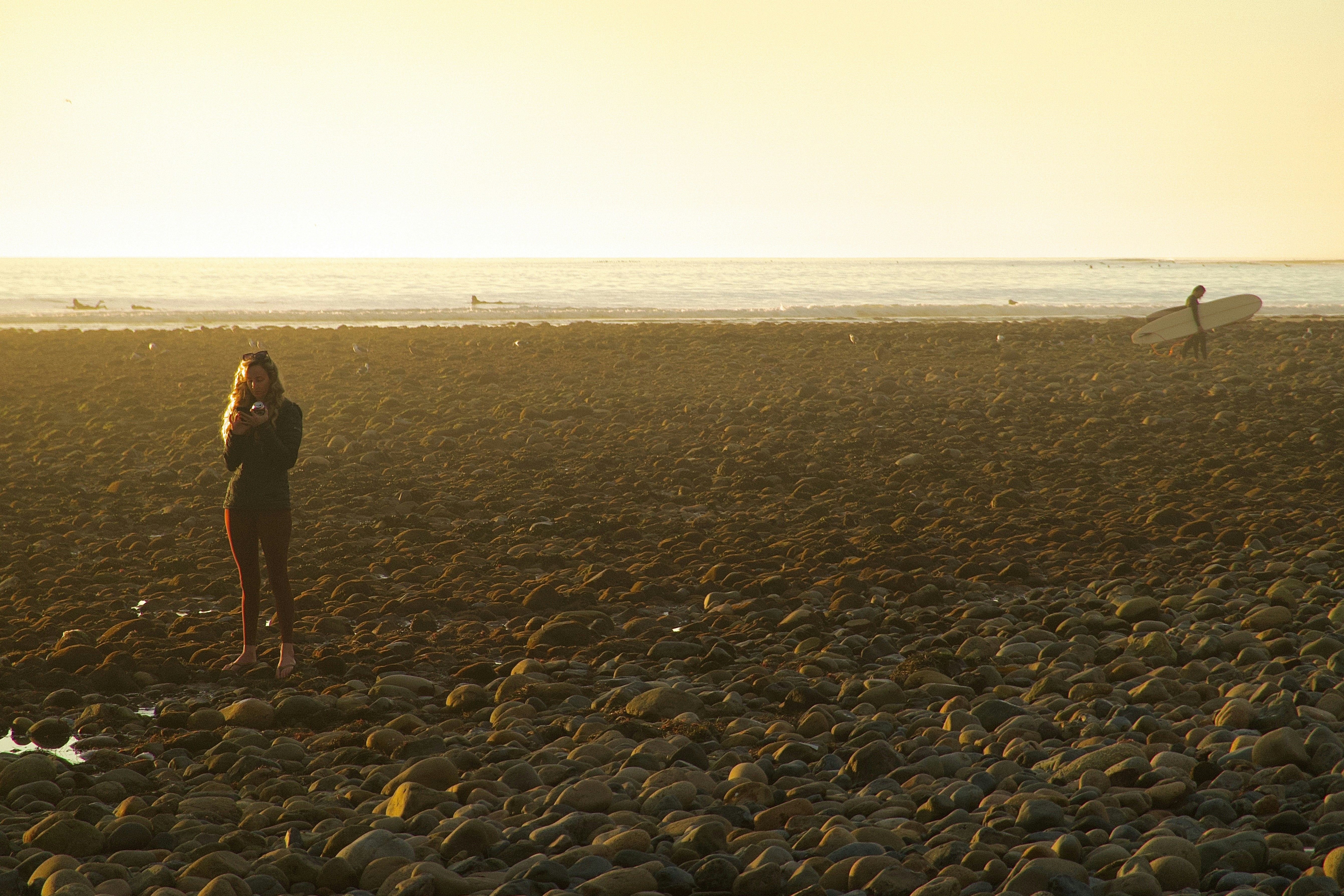 A woman standing on a rocky beach next to the ocean photo – Free San ...