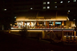 A restaurant lit up at night on the side of a river