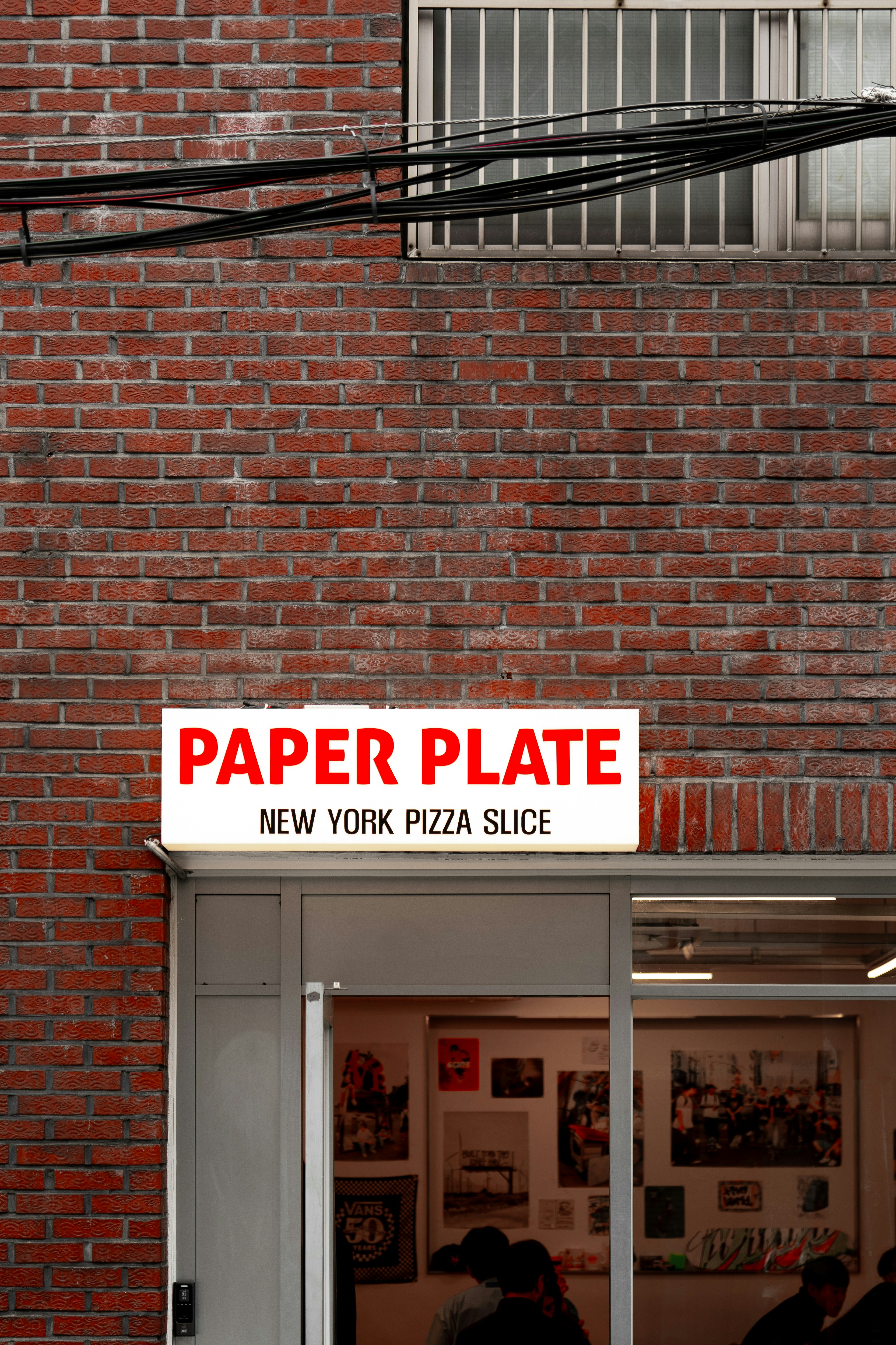 A red brick building with a sign that says paper plate new york pizza slice