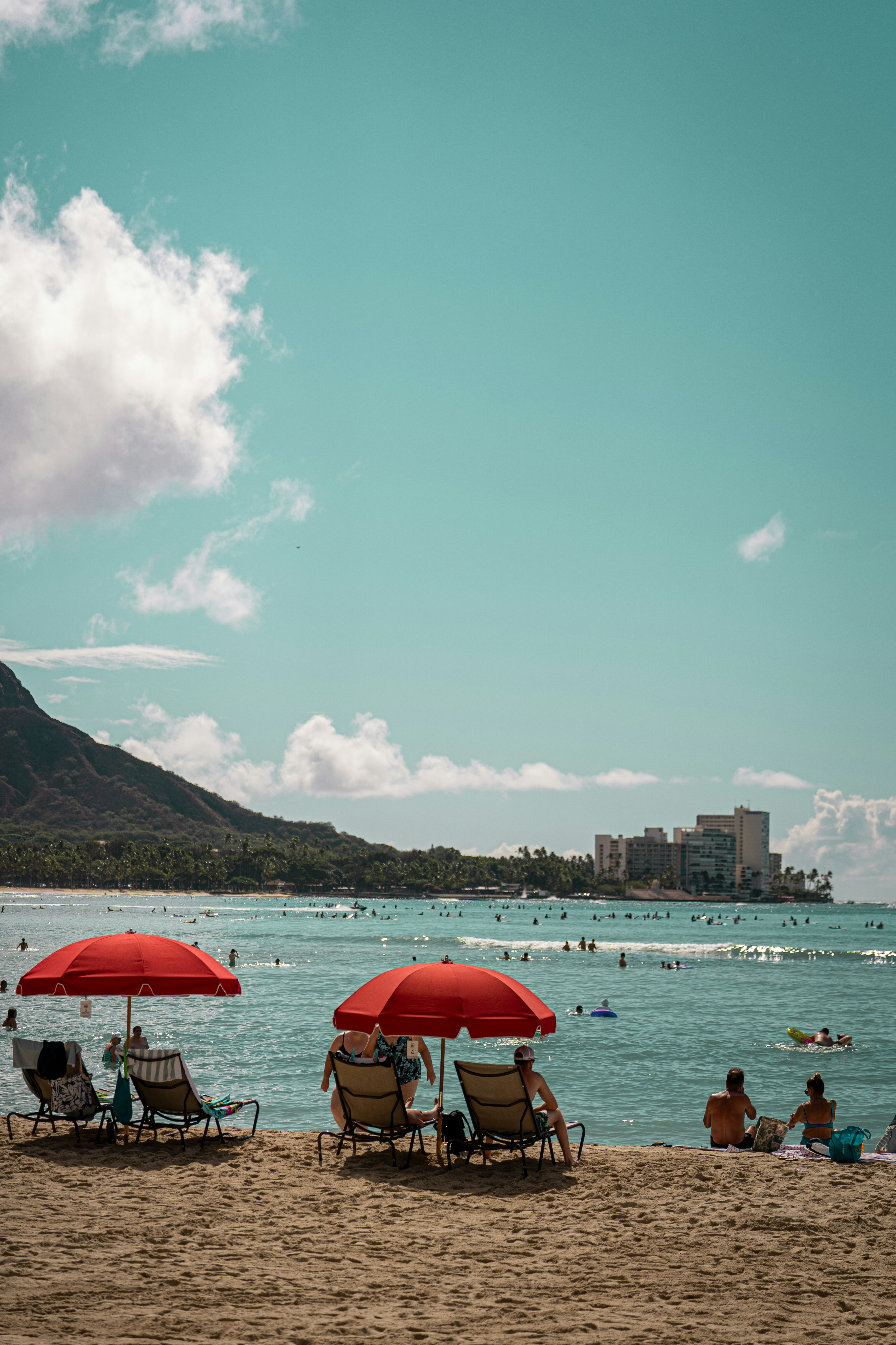 A group of people sitting on top of a sandy beach